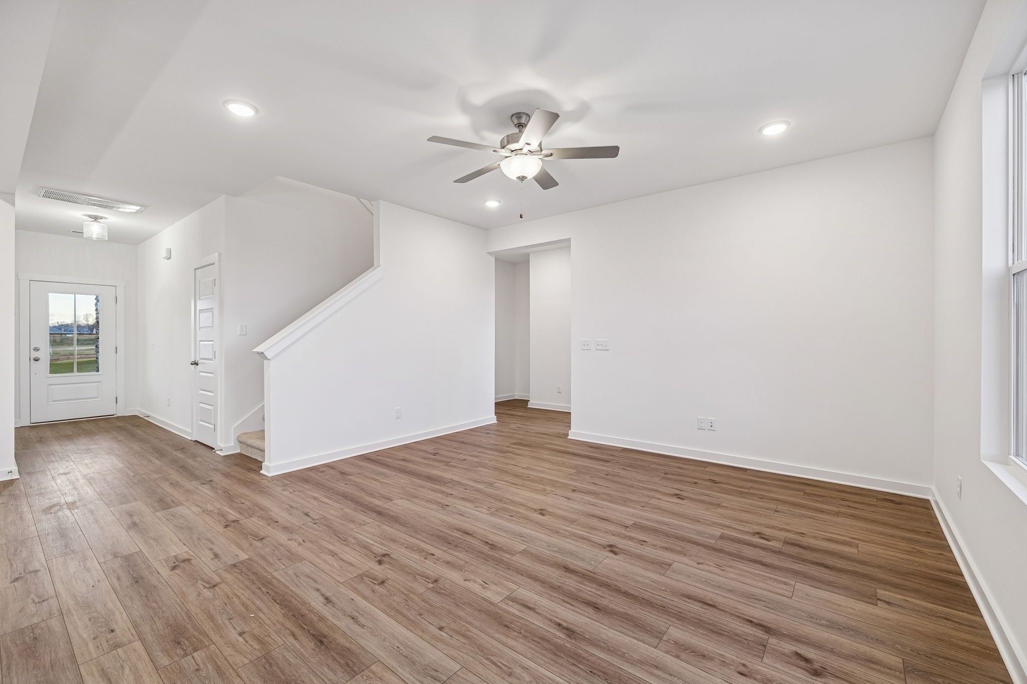 Bright entry foyer with hardwood floors, white staircase, ceiling fan, and natural light in The Willow 4-bedroom home, White House, TN