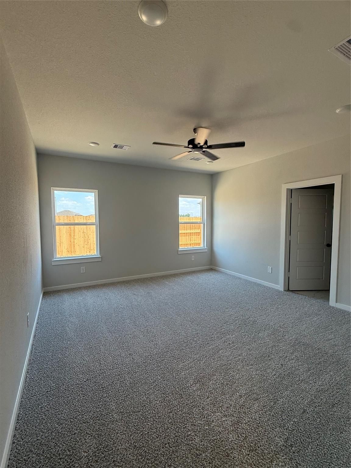Spacious bedroom with plush carpet and ceiling fan in The Sorrento E floor plan at Sundance Cove, Crosby, Texas.