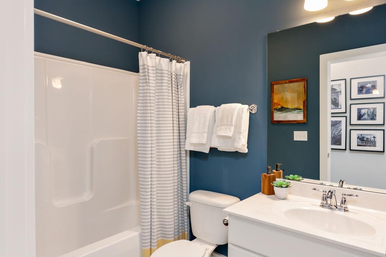 The Rockford master bathroom by Davidson Homes: navy walls, white subway tile tub-shower with striped curtain, sleek vanity