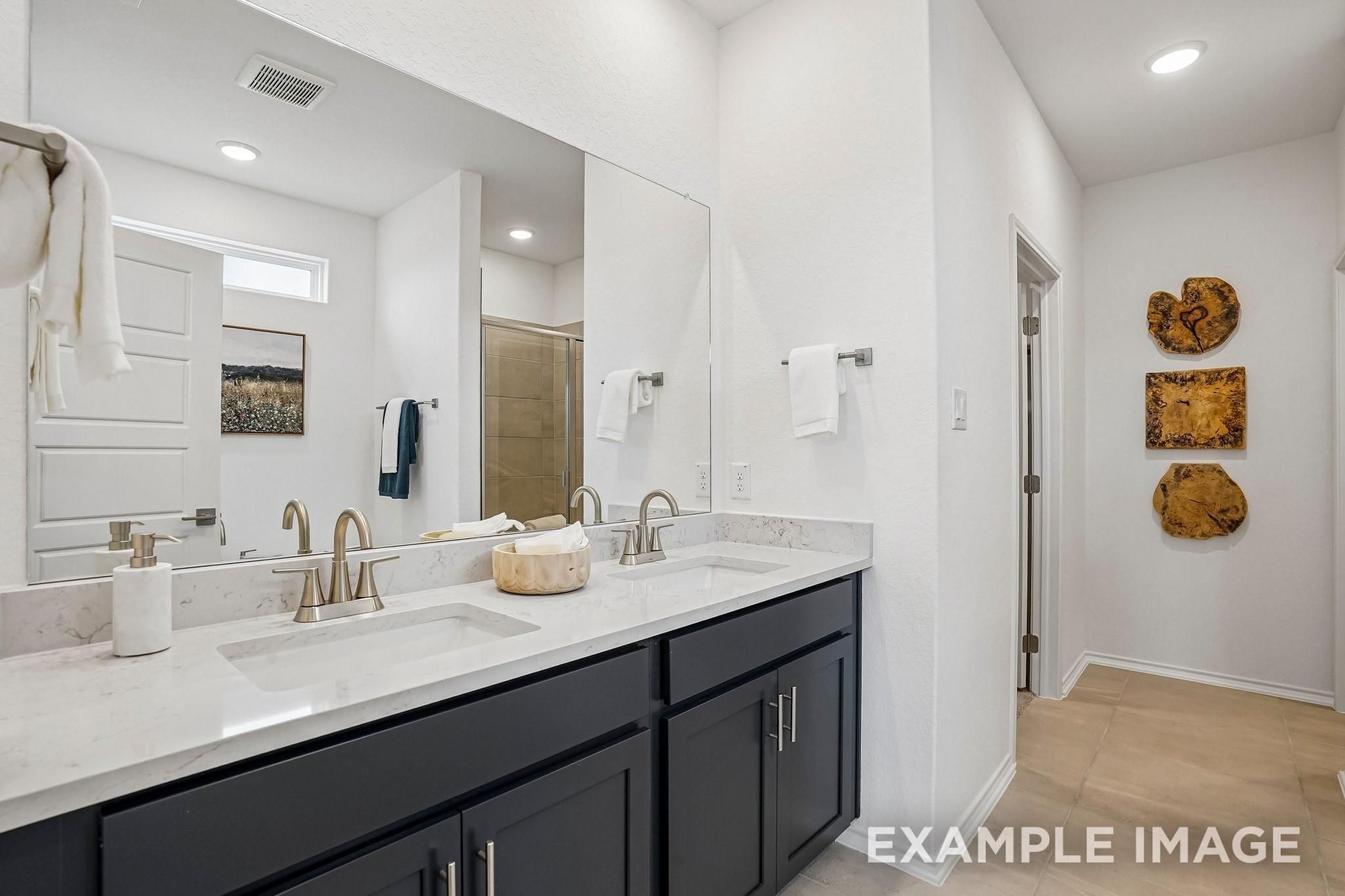 Double vanity bathroom with marble countertops, dark cabinets, and large mirror in Davidson Homes The Ashport J, Crosby, Texas