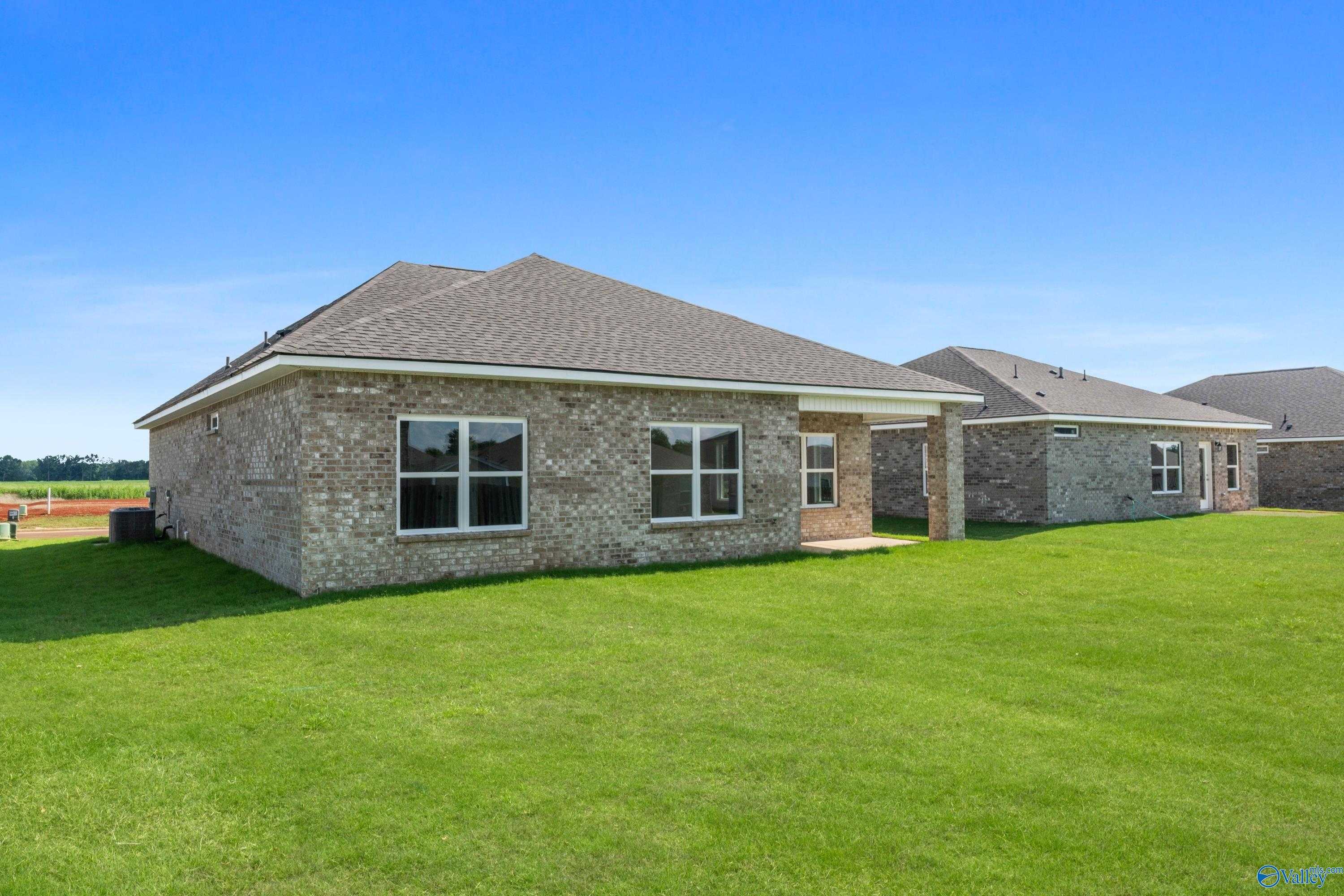 Brick single-story home with gabled roof, windows, covered carport, lush green lawn, blue sky in Clearview, Hazel Green, Alabama - Davidson Homes Franklin C