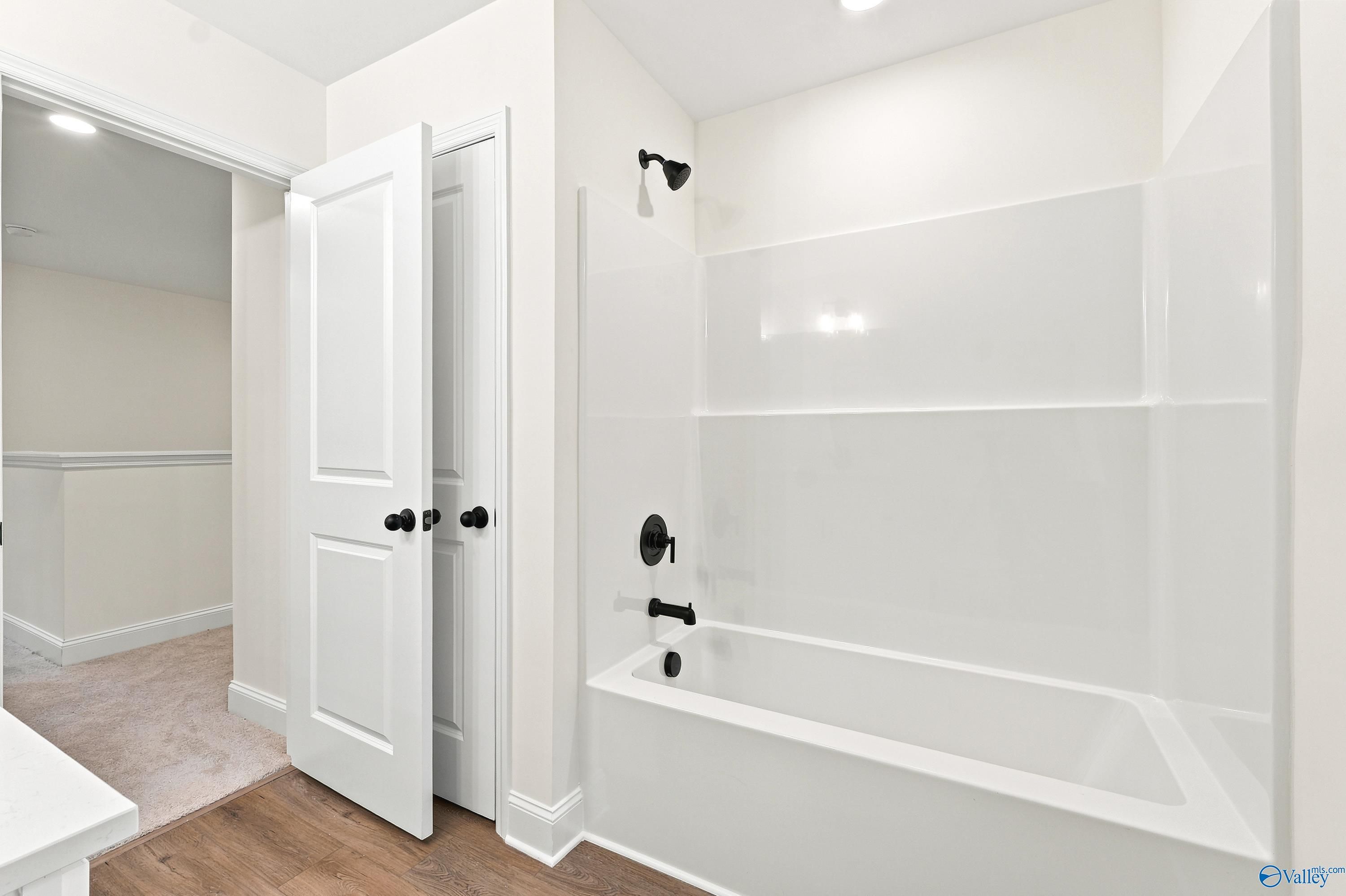 Modern bathroom with white tub-shower combo and black fixtures in The Shelby D floor plan by Davidson Homes in Cullman, AL.