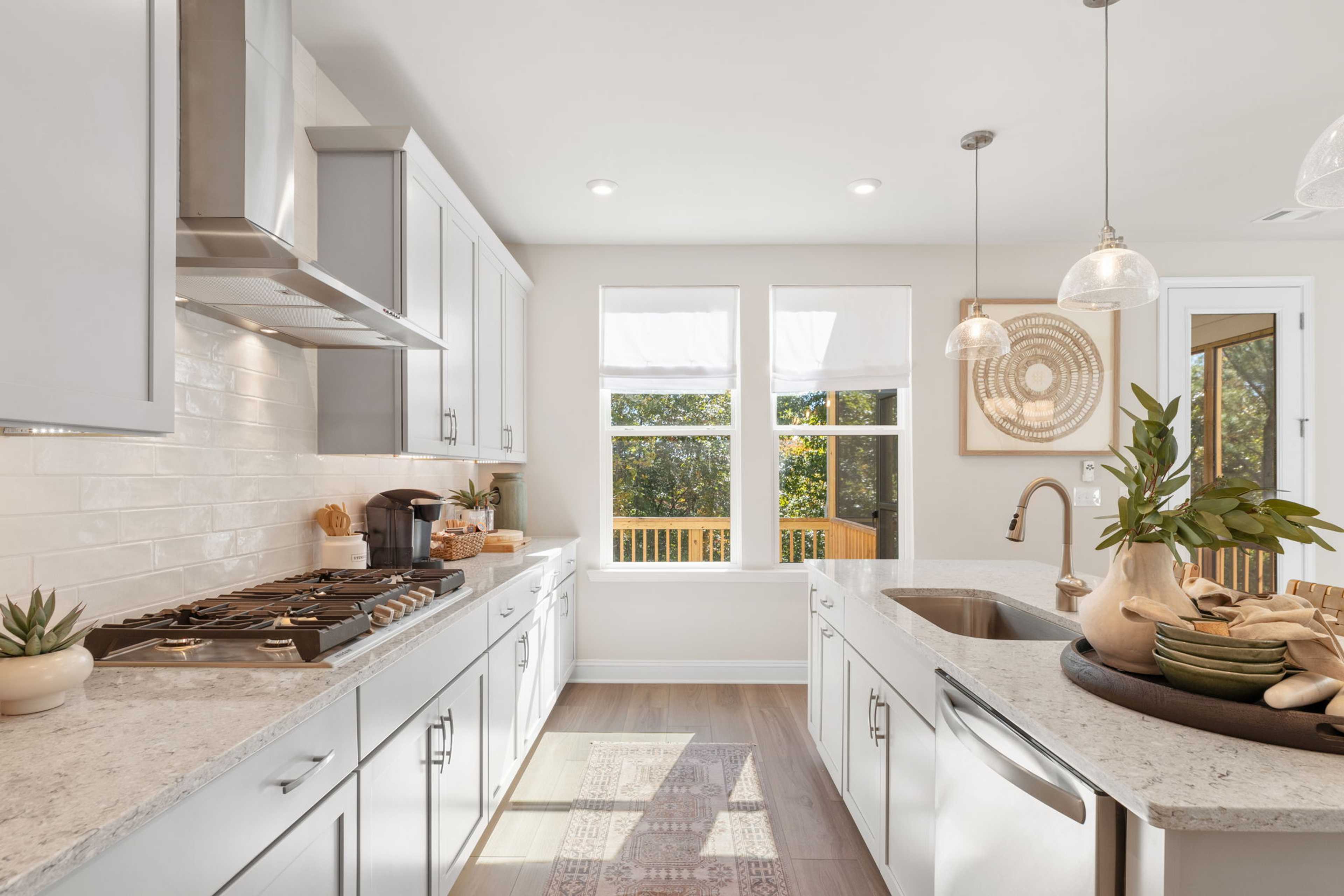 Bright modern kitchen at Melody Lakeside Estates in Buford GA with white shaker cabinets, quartz island, and deck view