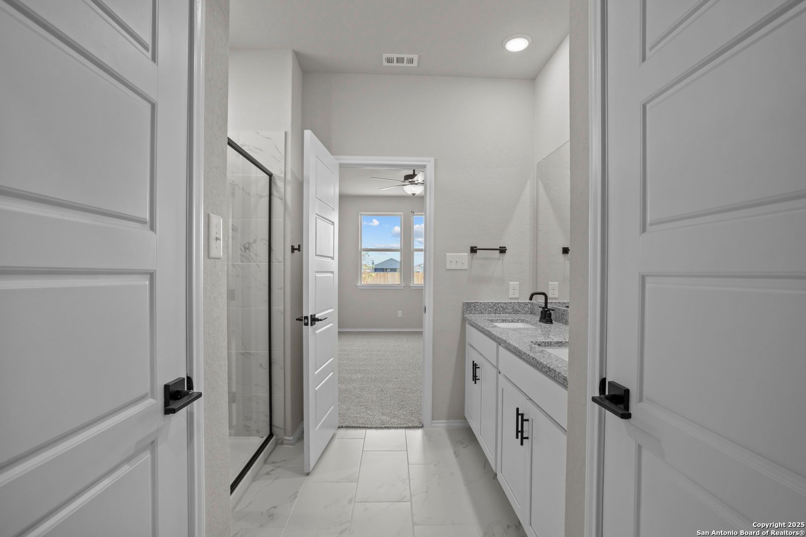 Modern master bathroom featuring walk-in shower, white double vanity, and window view in Davidson Homes The Daphne H, Seguin, Texas