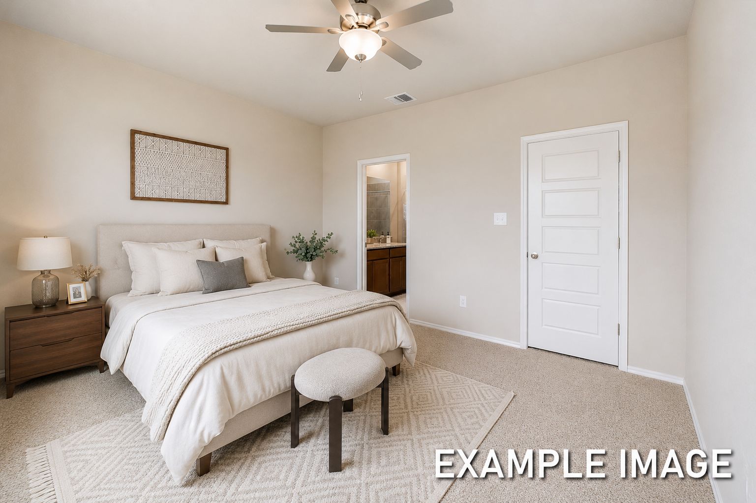 Spacious master suite on the main floor of The Comal featuring neutral decor, plush bedding, and an attached bathroom.