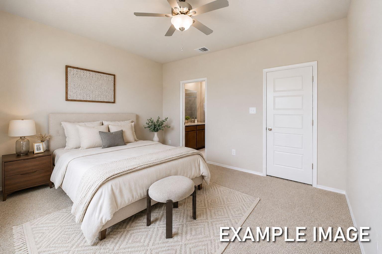 Spacious master suite on the main floor of The Comal featuring neutral decor, plush bedding, and an attached bathroom.