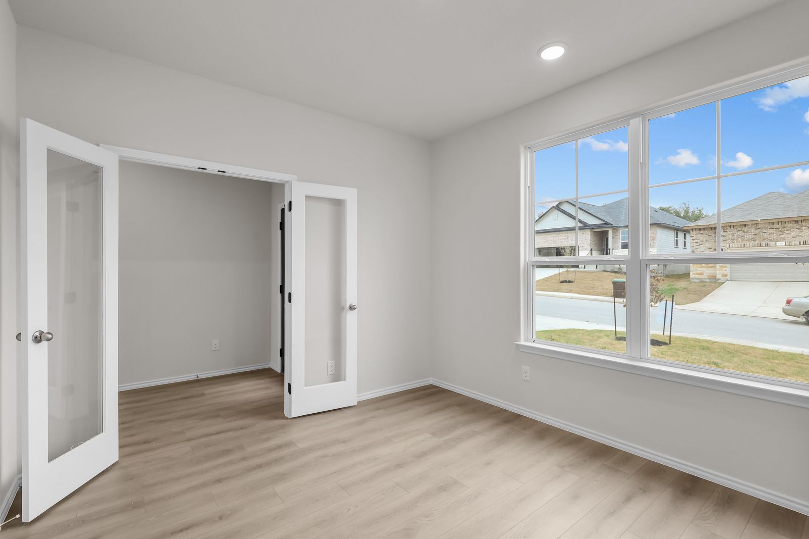 Bright study room with French doors and wood-look flooring in The Sequoia C home design in Converse, Texas.