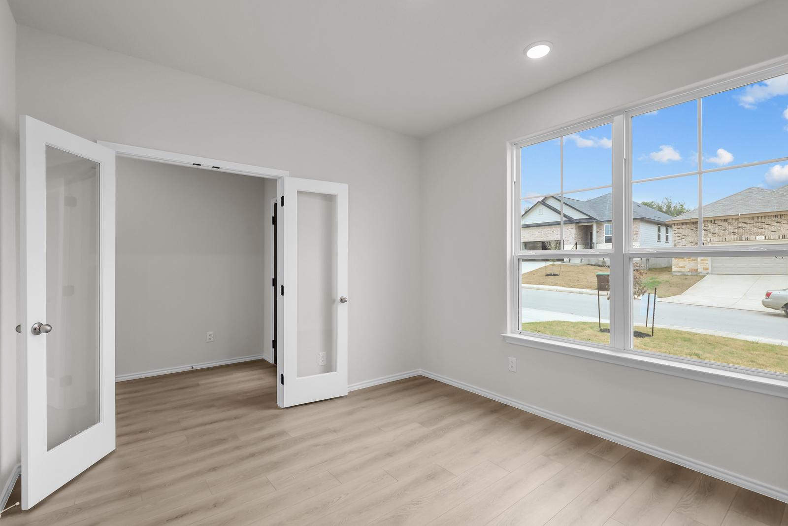 Bright study room with French doors and wood-look flooring in The Sequoia C home design in Converse, Texas.