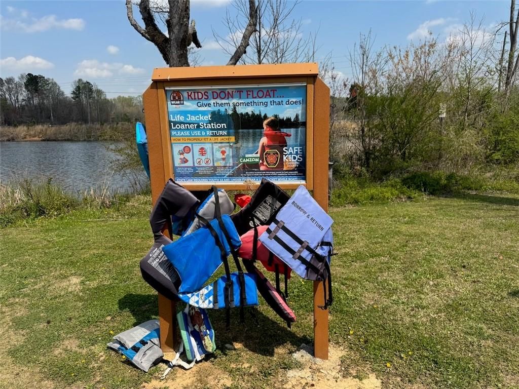 Loaner life jacket station with colorful PFDs and safety sign near river in The Bluffs, Canton, Georgia community