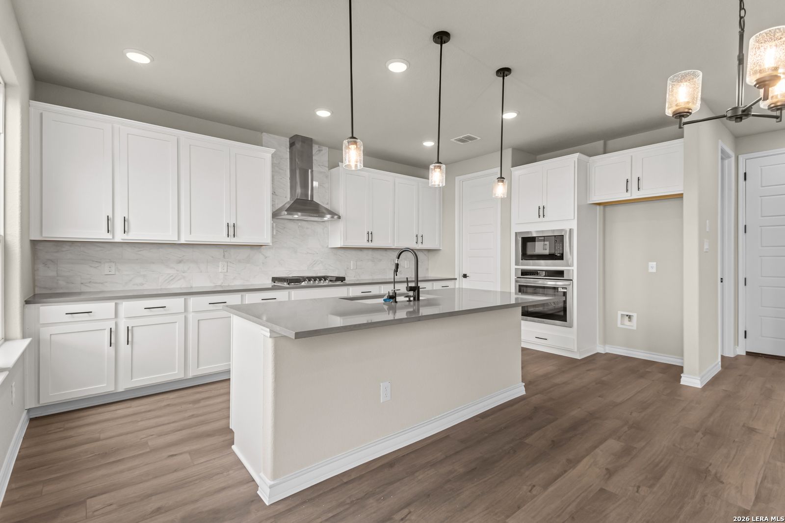 Modern kitchen with white cabinets, quartz countertops, and stainless steel appliances in The Danbury H, Castroville, TX.