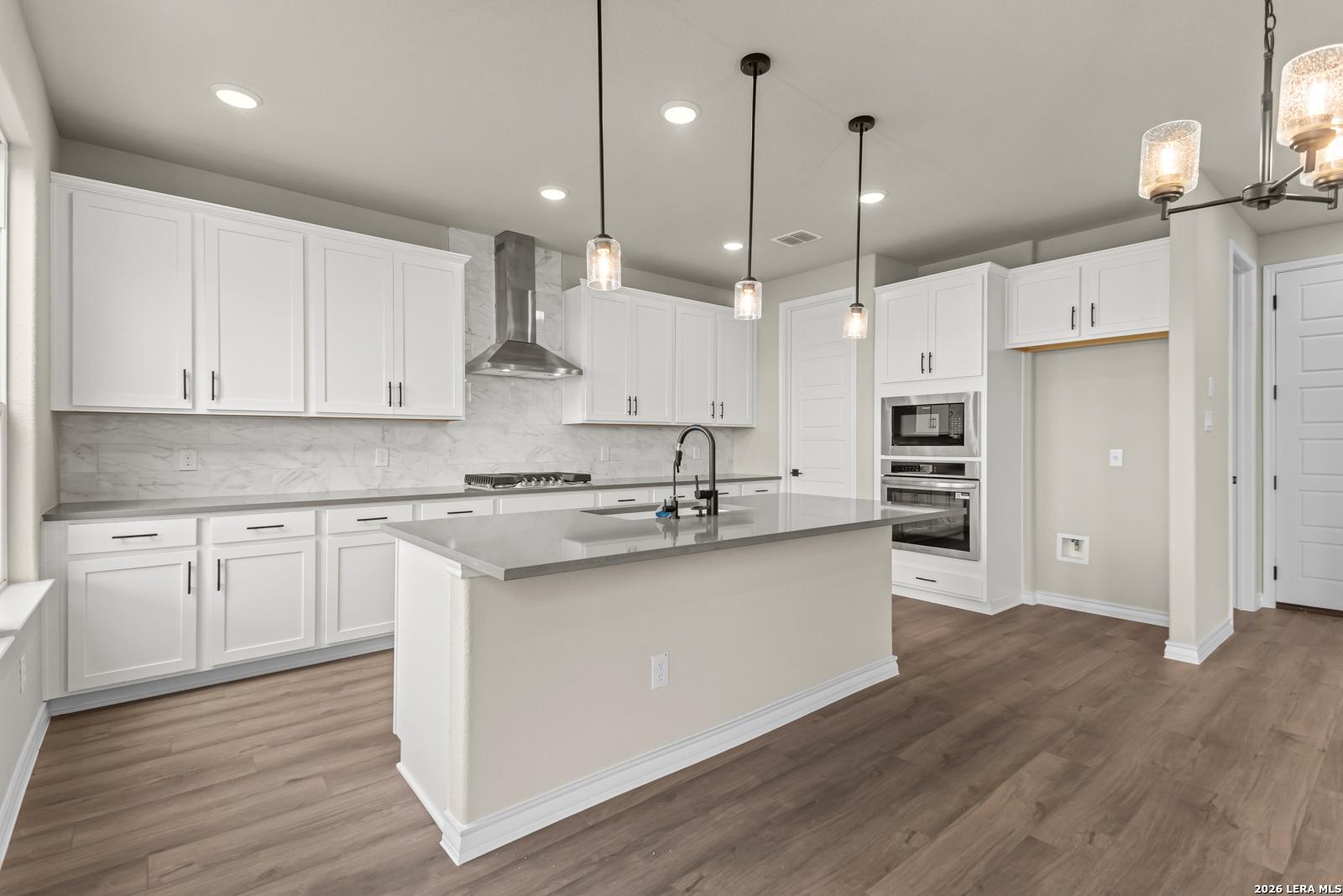 Modern kitchen with white cabinets, quartz countertops, and stainless steel appliances in The Danbury H, Castroville, TX.