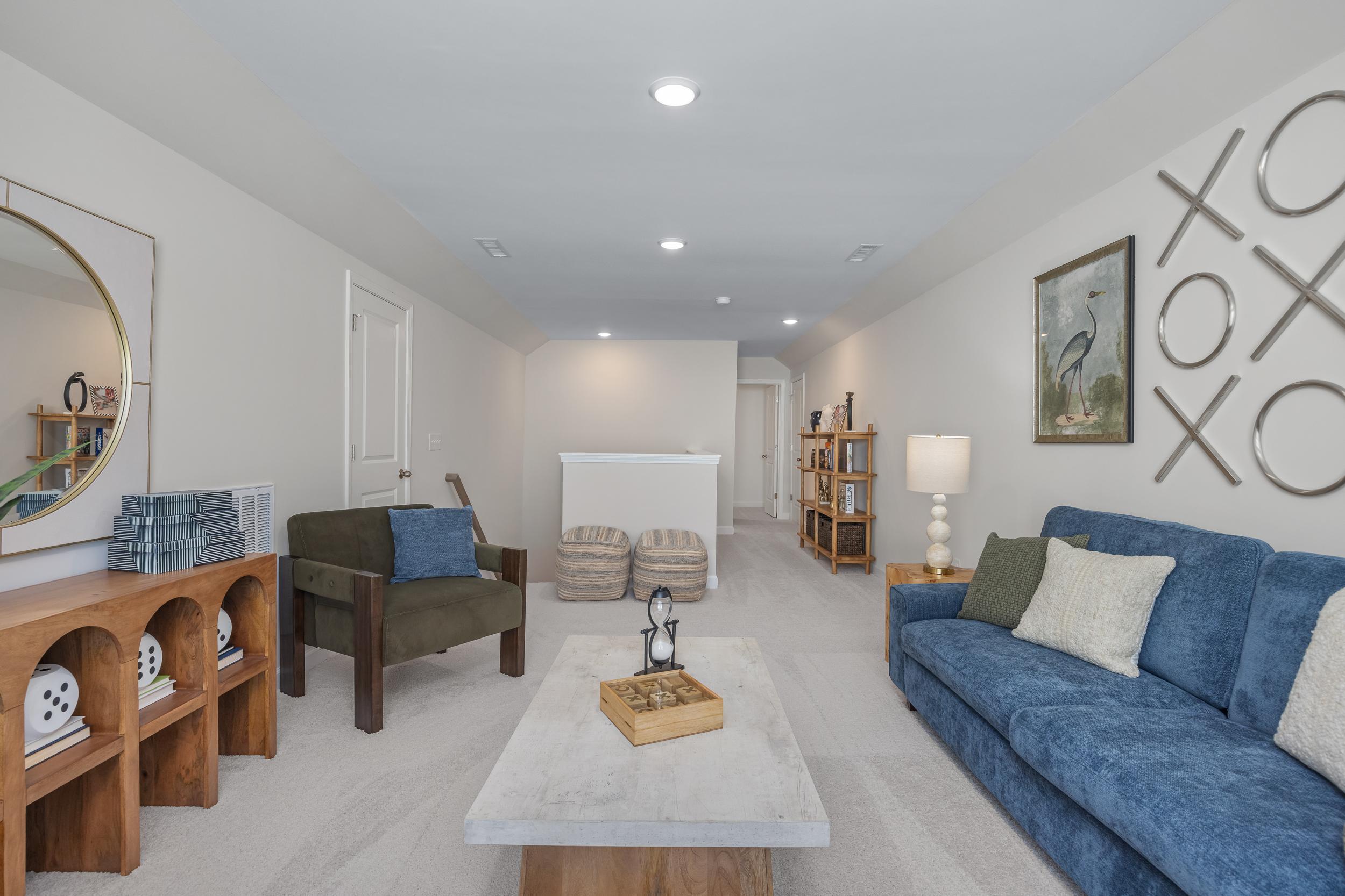 Cozy bonus room at Sage on North Main in Wake Forest NC with blue velvet sofa, wooden shelves, round mirror, and modern decor