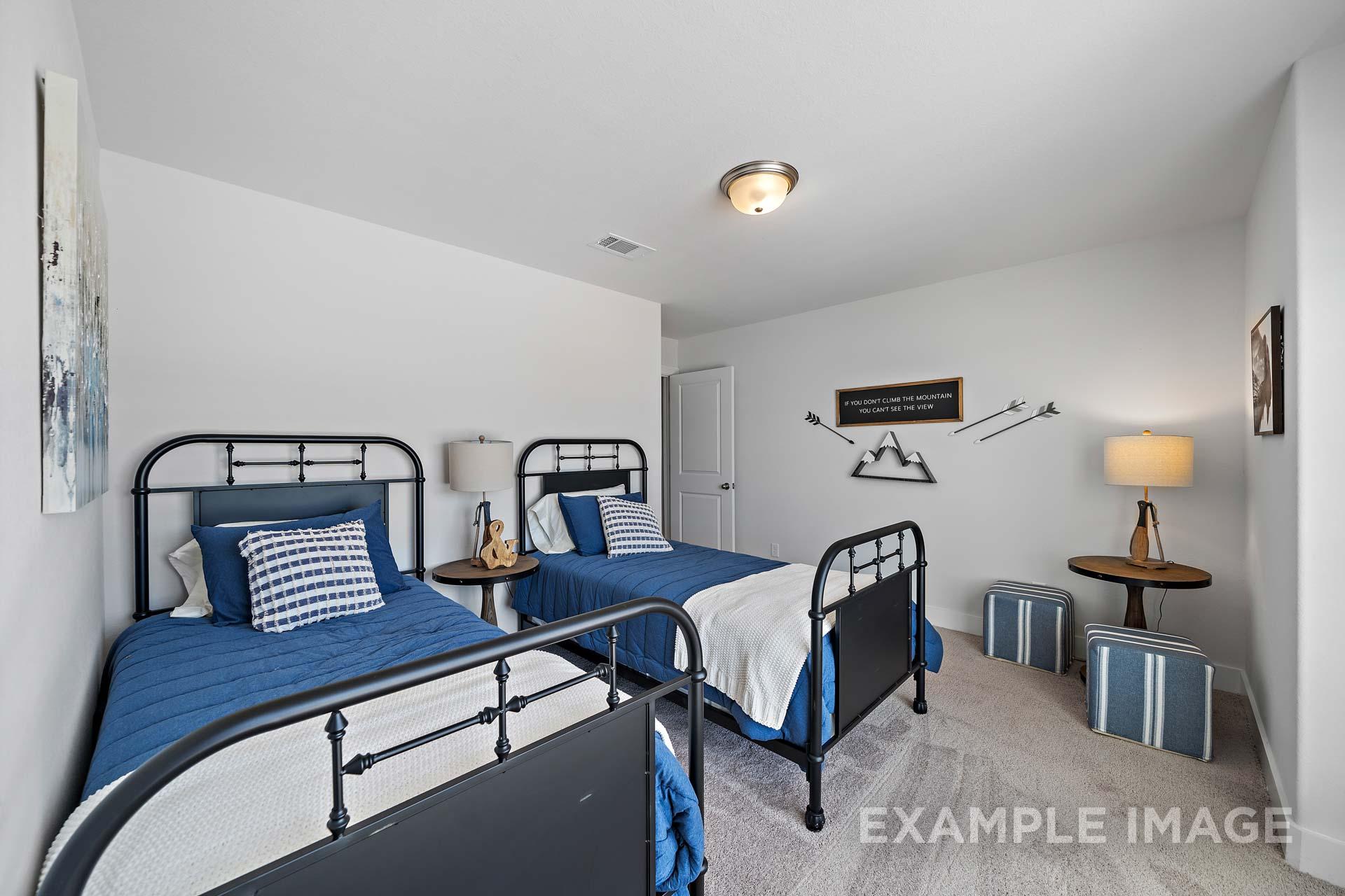 Spacious youth bedroom in The Rose B featuring twin beds with blue bedding, black frames, and adventure-themed wall decor