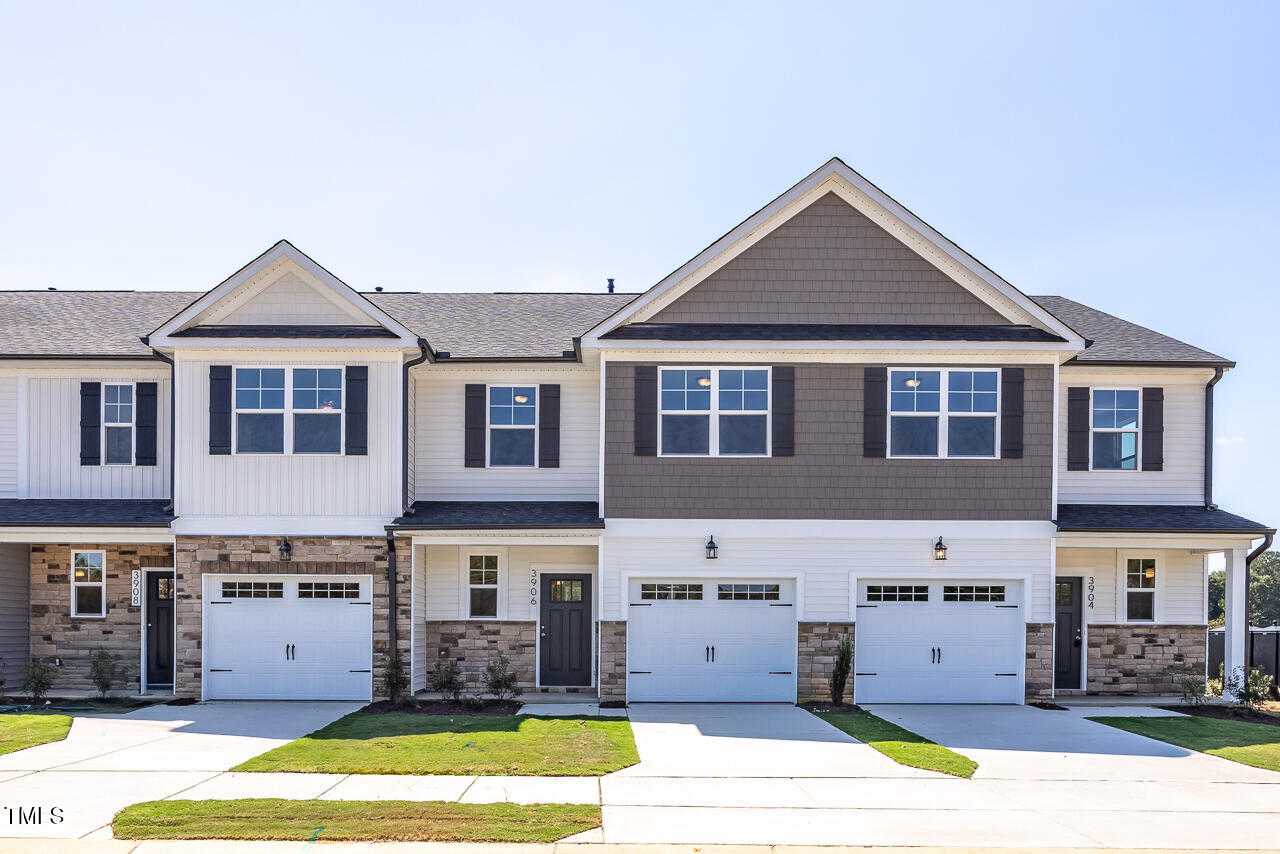 Modern 2-story townhomes with white siding, gray gables, stone bases, and 1-car garages in Springvale, Fuquay-Varina, NC by Davidson Homes