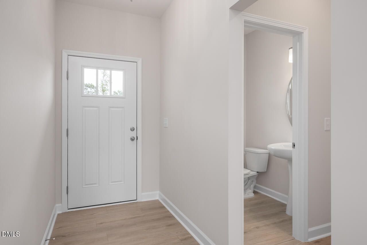 Entryway with white front door and access to half bath in The Graham Interior floor plan by Davidson Homes in Fuquay-Varina.