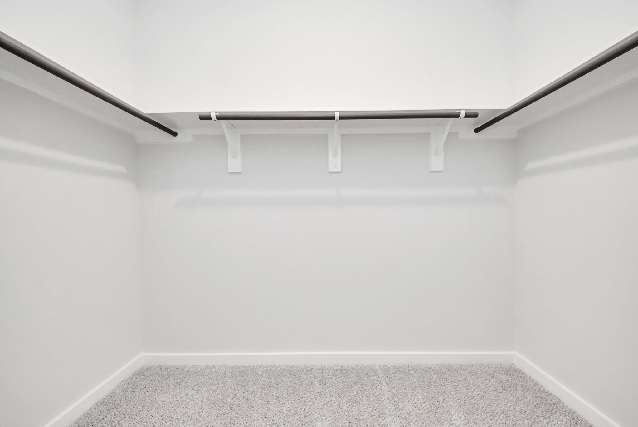 Walk-in closet with ample shelving and hanging rods in The Blanco F floor plan at Spring Branch Crossing, Conroe, Texas.