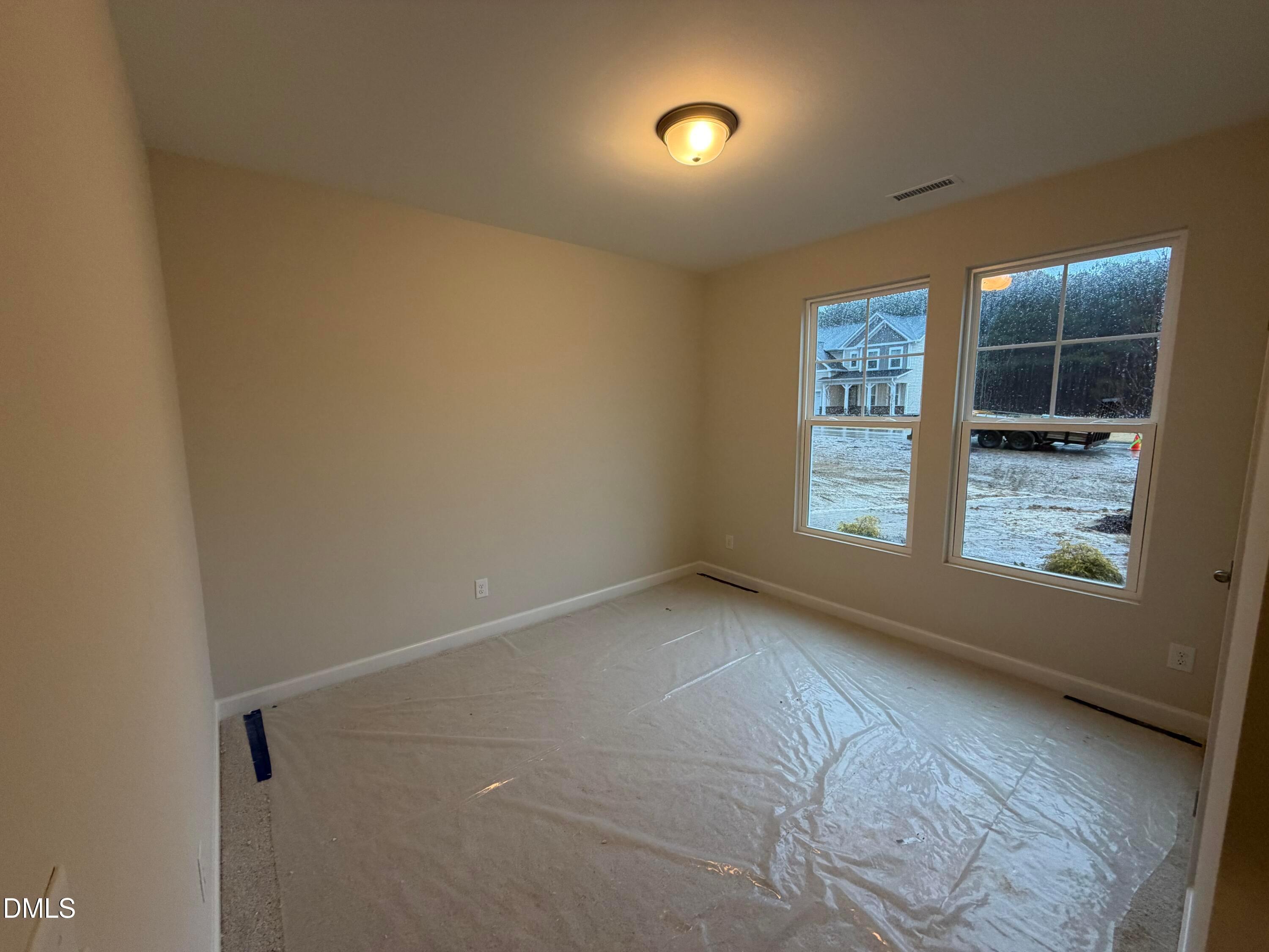 Spacious empty bedroom with neutral walls, large windows overlooking snowy neighborhood in Davidson Homes The Daphne C, Lillington, NC