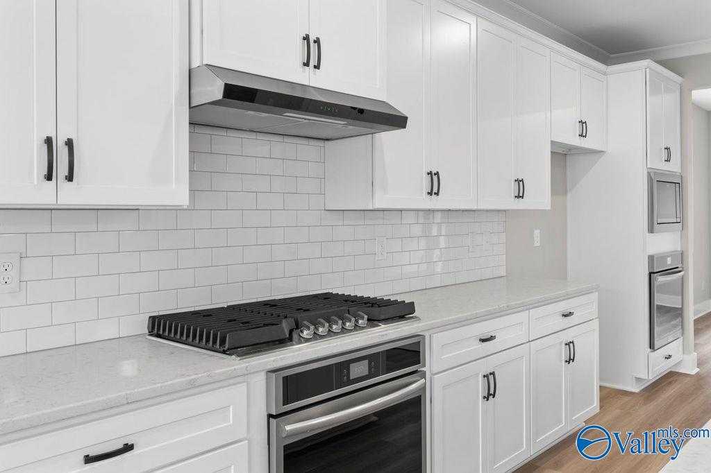 Modern white kitchen featuring subway tile backsplash, stainless steel gas range, and quartz counters in Evermore Homes The Oxford, Owens Cross Roads