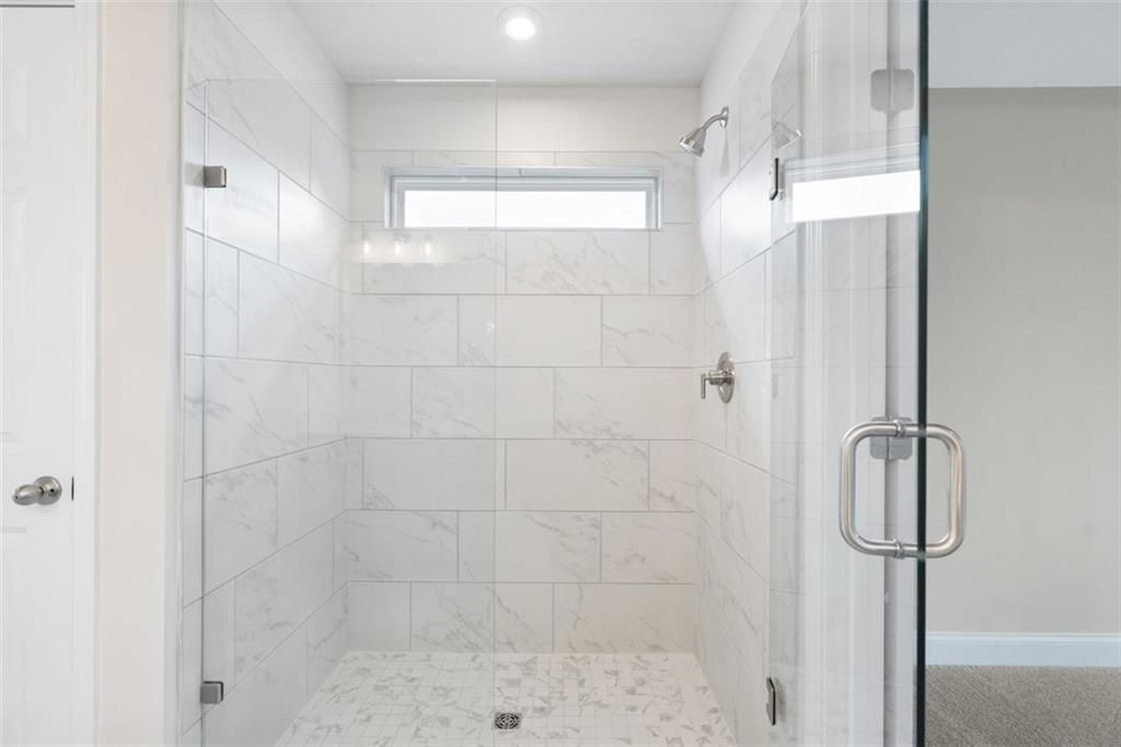 Elegant frameless glass shower with white subway tiles, rainfall showerhead in master bath of Davidson Homes The Willow B, Hoschton, GA