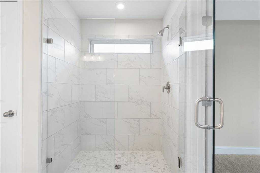 Elegant frameless glass shower with white subway tiles, rainfall showerhead in master bath of Davidson Homes The Willow B, Hoschton, GA
