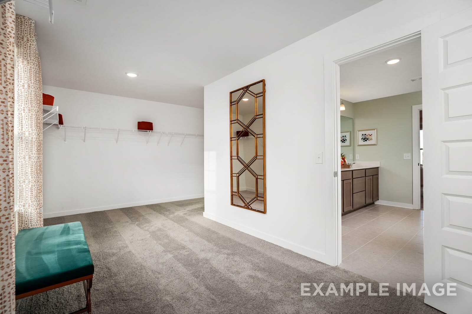 Spacious master suite in The Gordon B with arched mirror, teal bench, and open bathroom door, Davidson Homes design