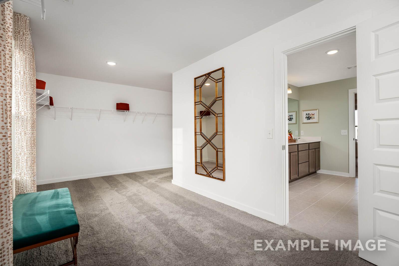 Upper floor hallway in The Gordon C by Davidson Homes, featuring arched mirror, teal bench, coat hooks, and adjacent bathroom vanity
