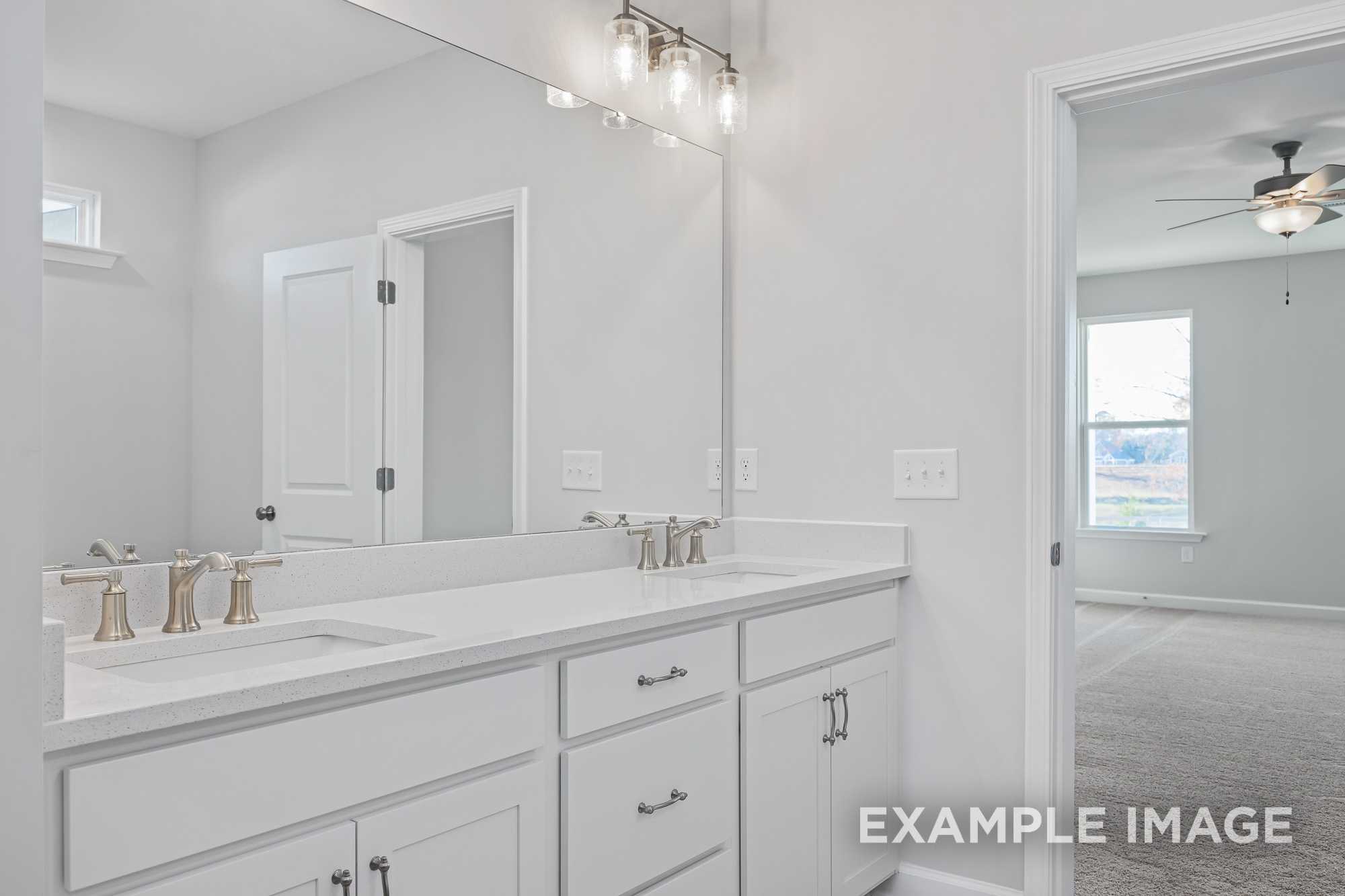 Modern master bathroom in The Cypress D II with double white quartz vanity, framed mirror, and adjacent bedroom view