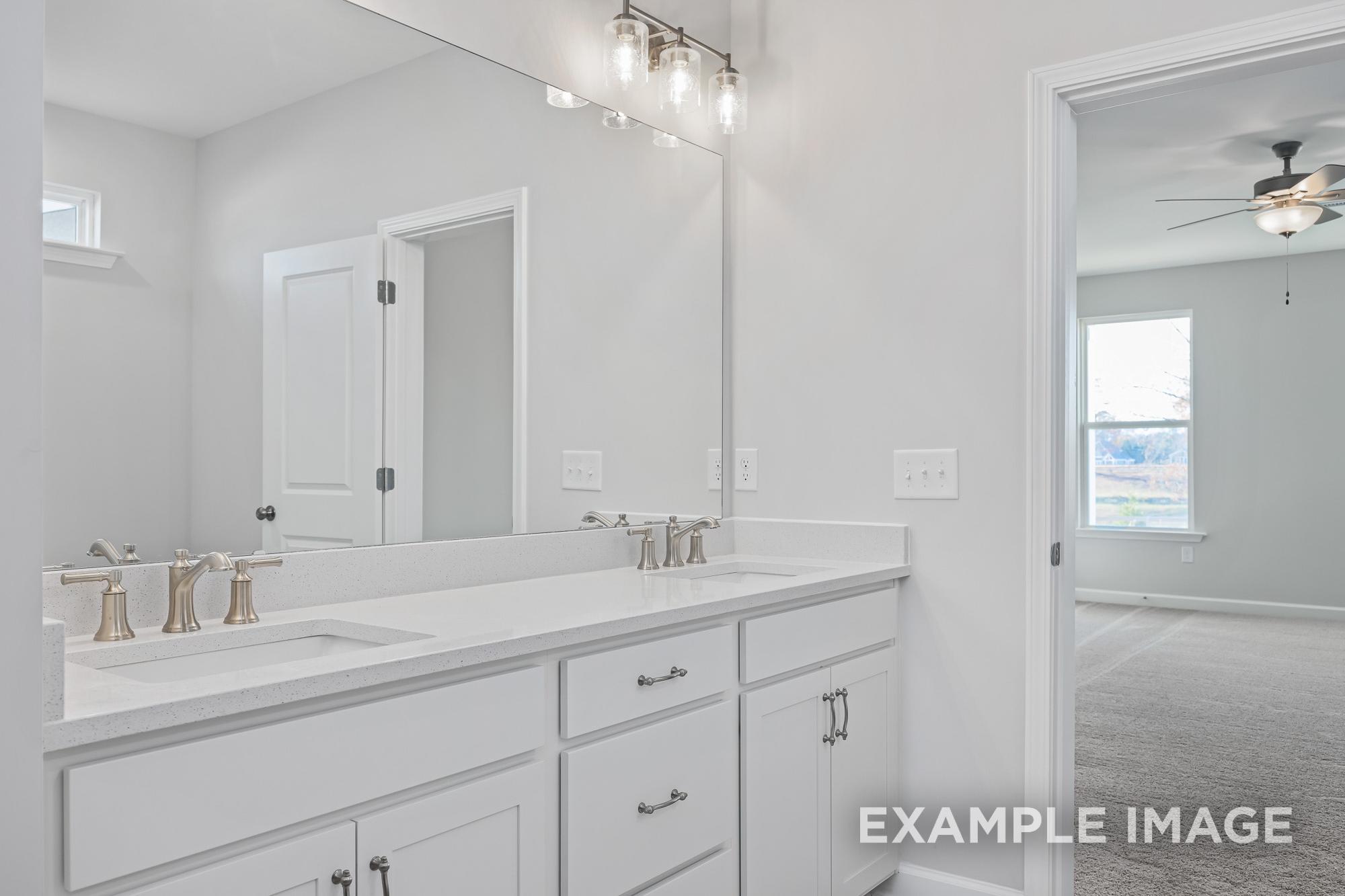 Spacious master bathroom in The Cypress C II with double white vanity, quartz countertop, and large mirror