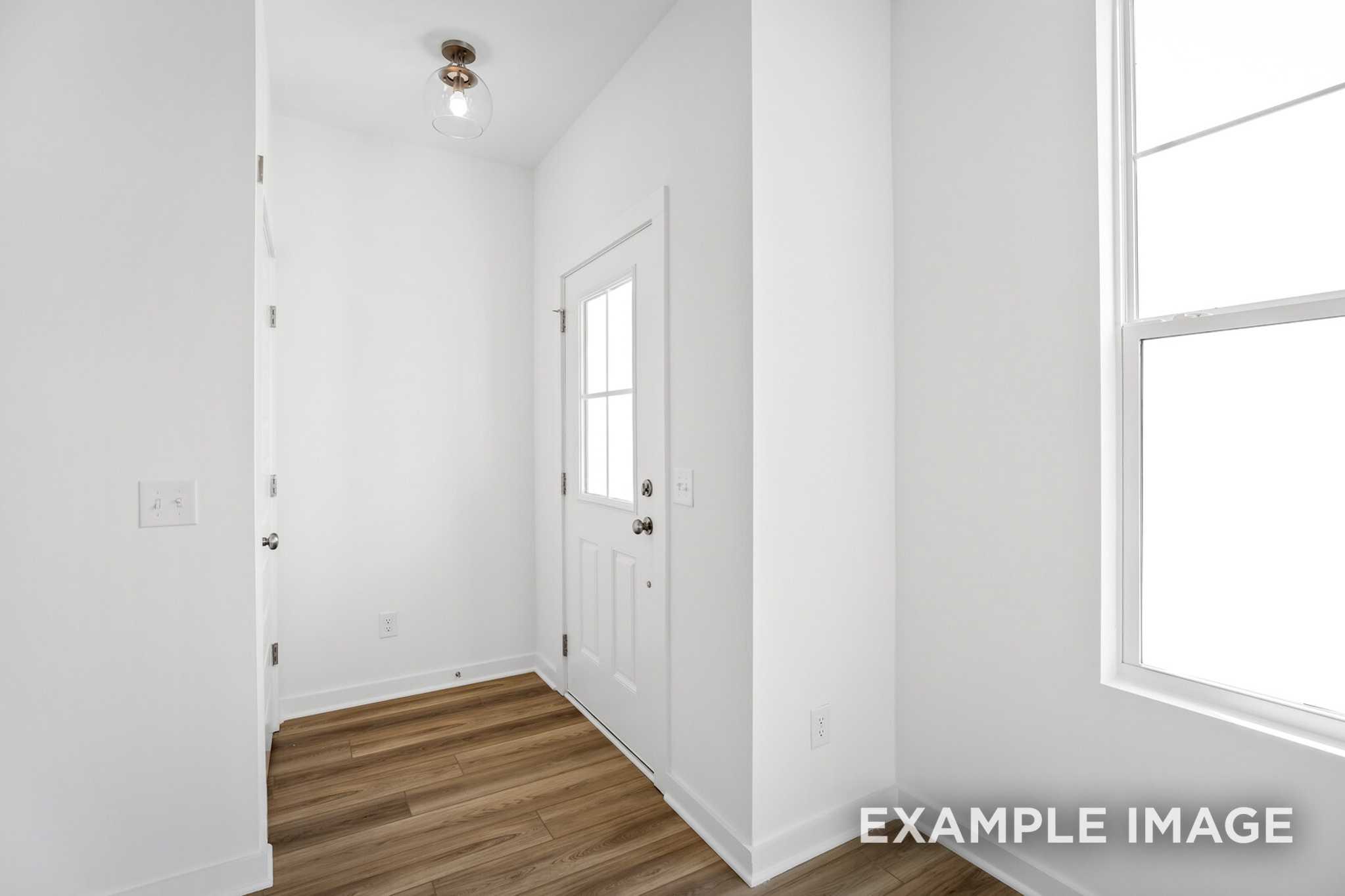 Bright entryway in The Murray B home design featuring white walls, hardwood floors, and glass door with sidelight