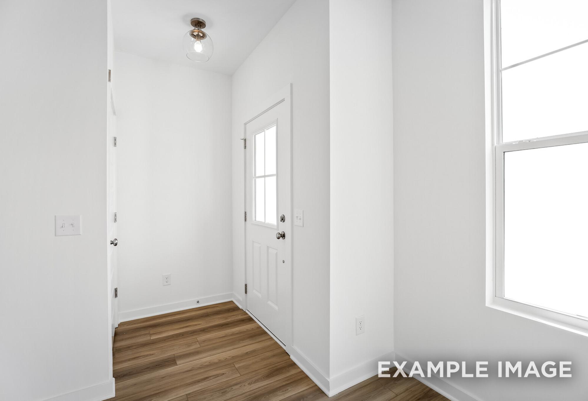 Bright entryway in The Murray B home design featuring white walls, hardwood floors, and glass door with sidelight