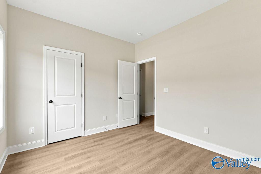 Neutral-toned secondary bedroom with wood-look flooring in The Camilla C floor plan at The Retreat at Cain Park, Hartselle.