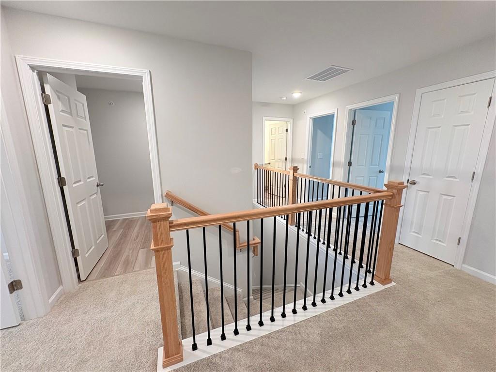 Upstairs hallway with bedroom doors and oak staircase railing in Davidson Homes The Wake E, Cumming, Georgia