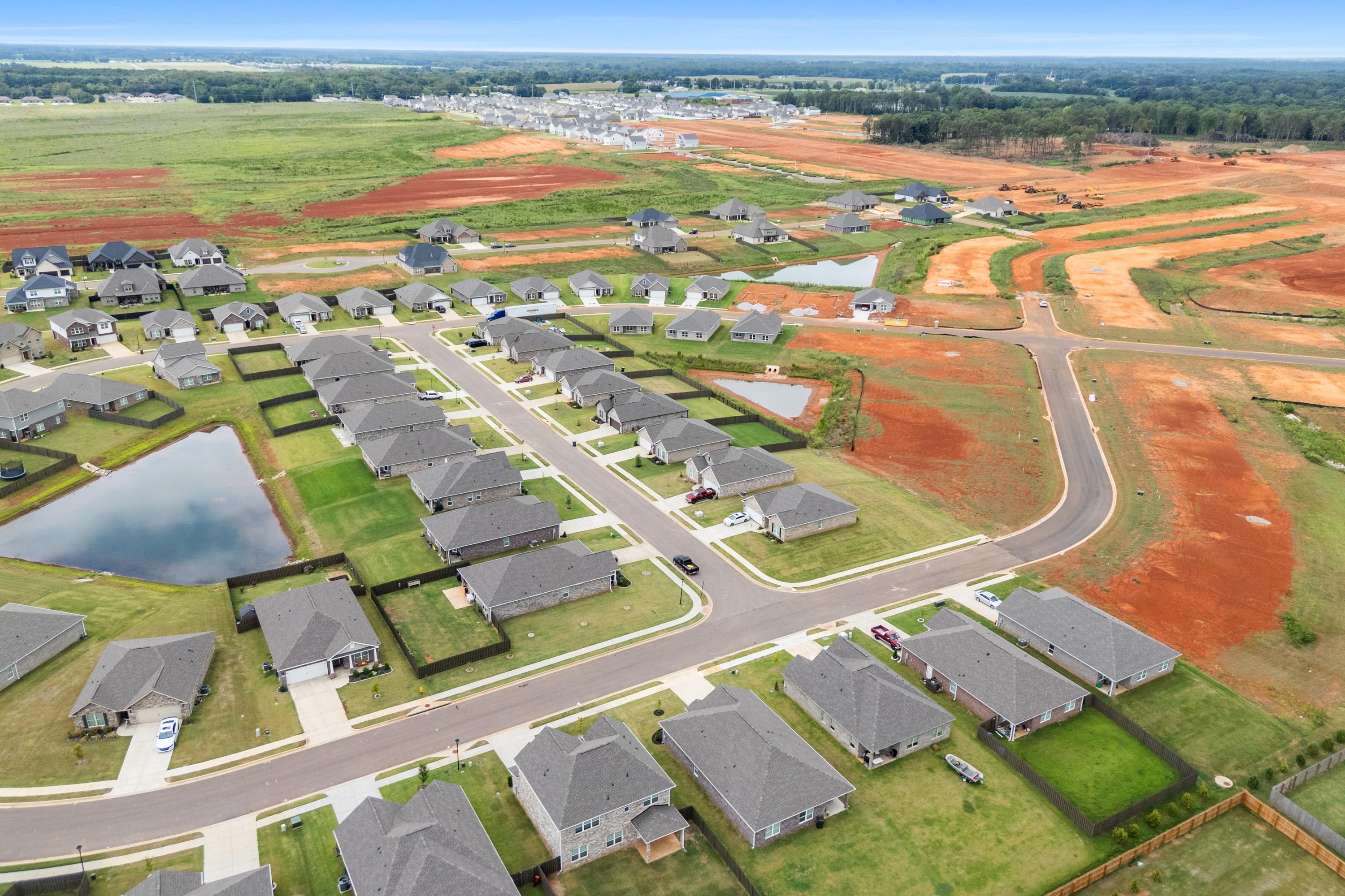 Aerial view of Heritage Lakes in New Market Alabama with new Davidson Homes, pond, streets and red clay fields