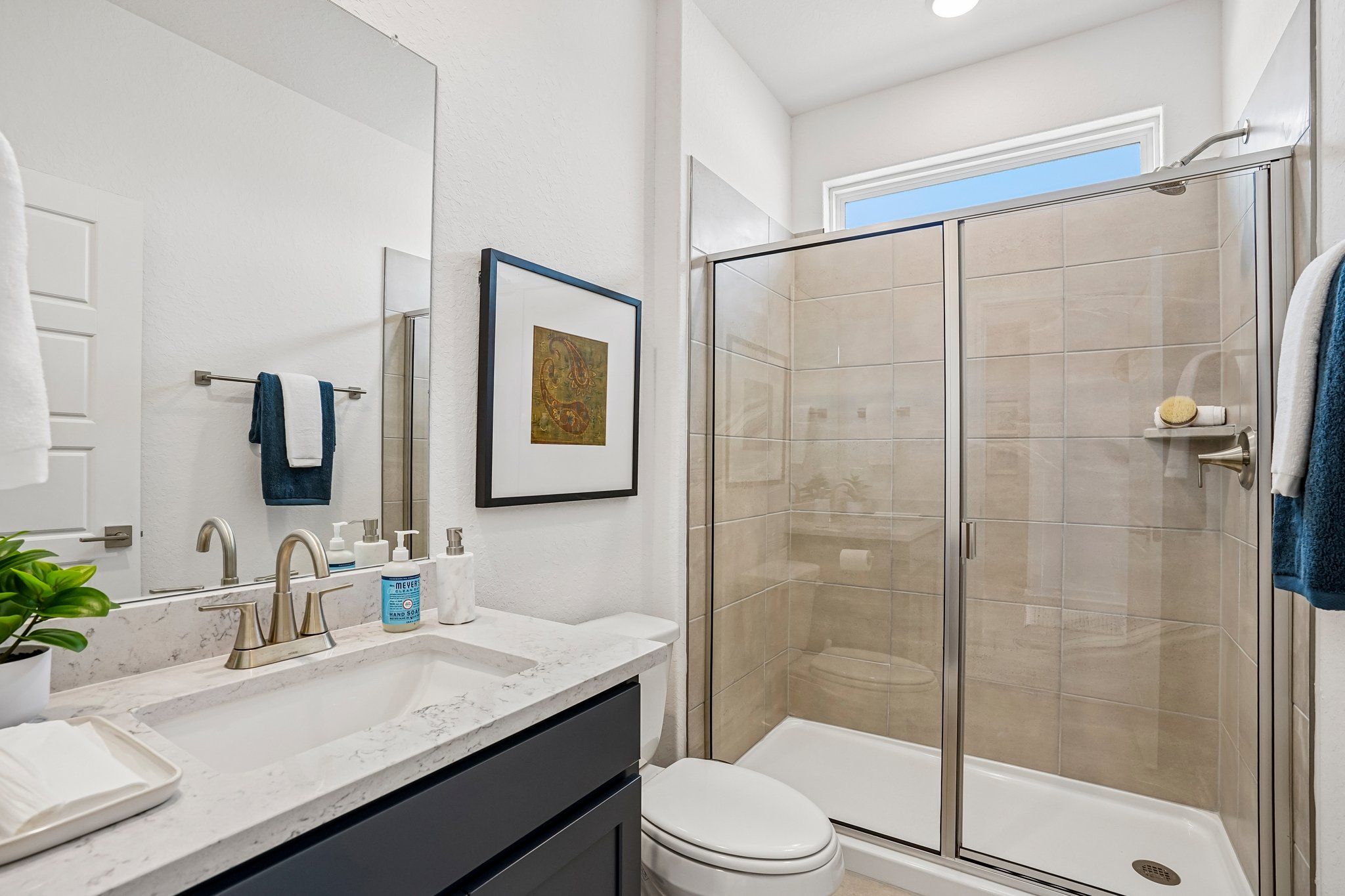 Modern bathroom at Morgan Meadows in San Antonio with marble vanity, dark cabinetry, and a walk-in glass shower by Davidson.