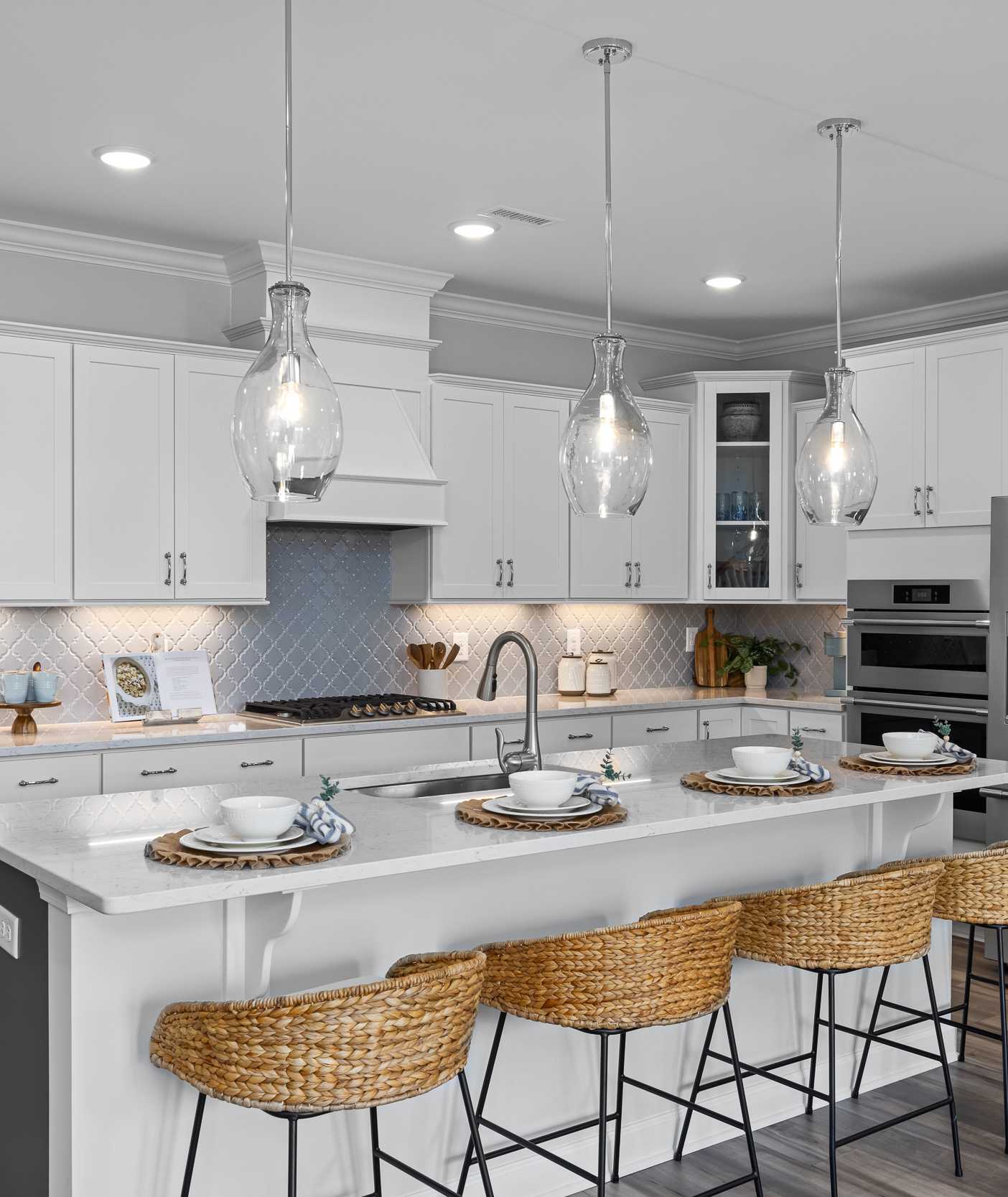 Modern white kitchen in Tobacco Road Angier NC by Davidson Homes with island bar stools pendant lights and stainless appliances