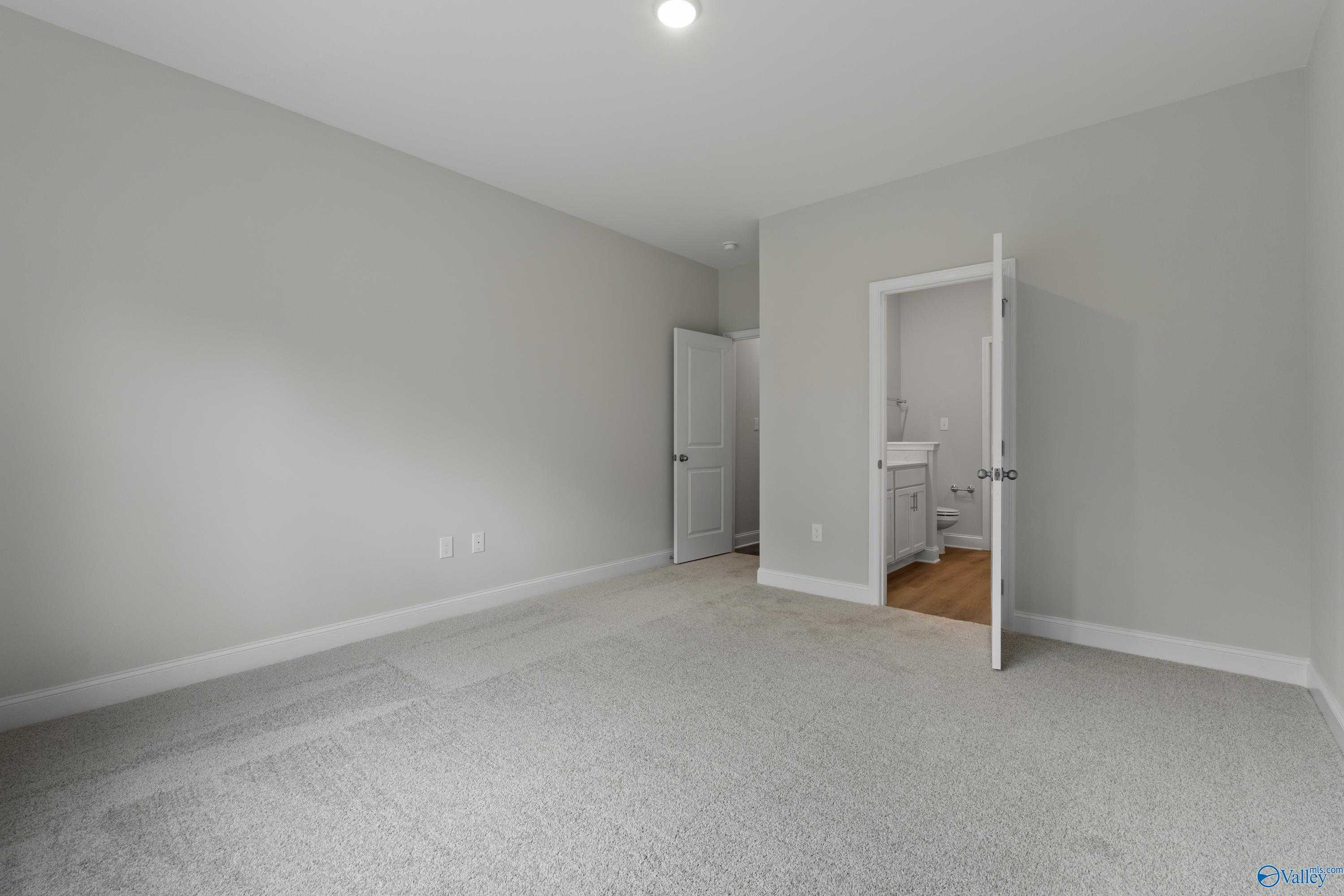 Light gray secondary bedroom with carpeted floor, open closet, and adjacent bathroom in Davidson Homes The Asheville C, Huntsville AL