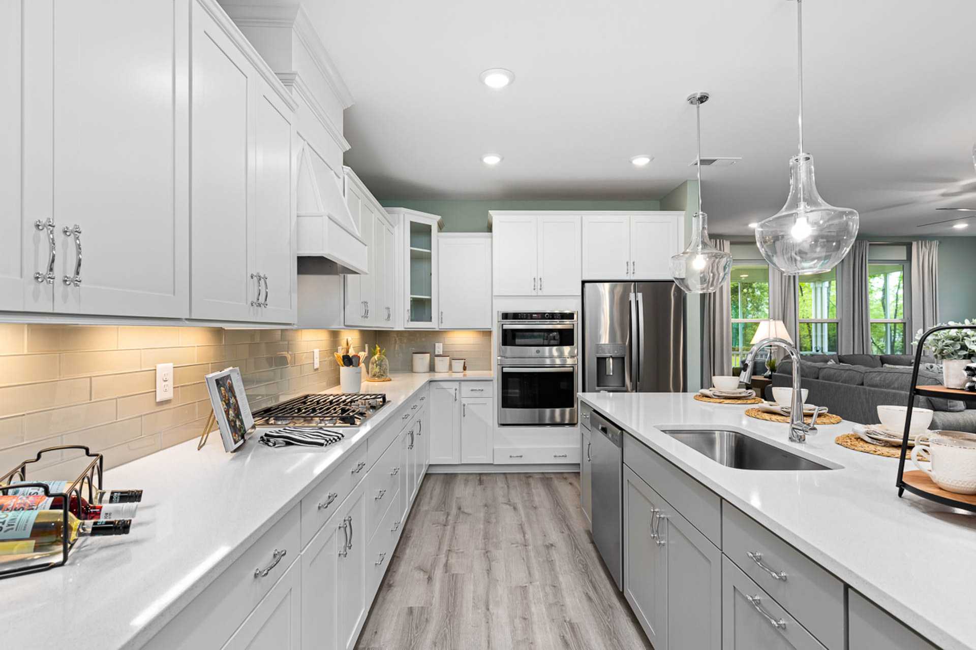 Spacious modern kitchen at Weatherford East in Angier NC with white shaker cabinets, gray island, stainless appliances, hardwood floors