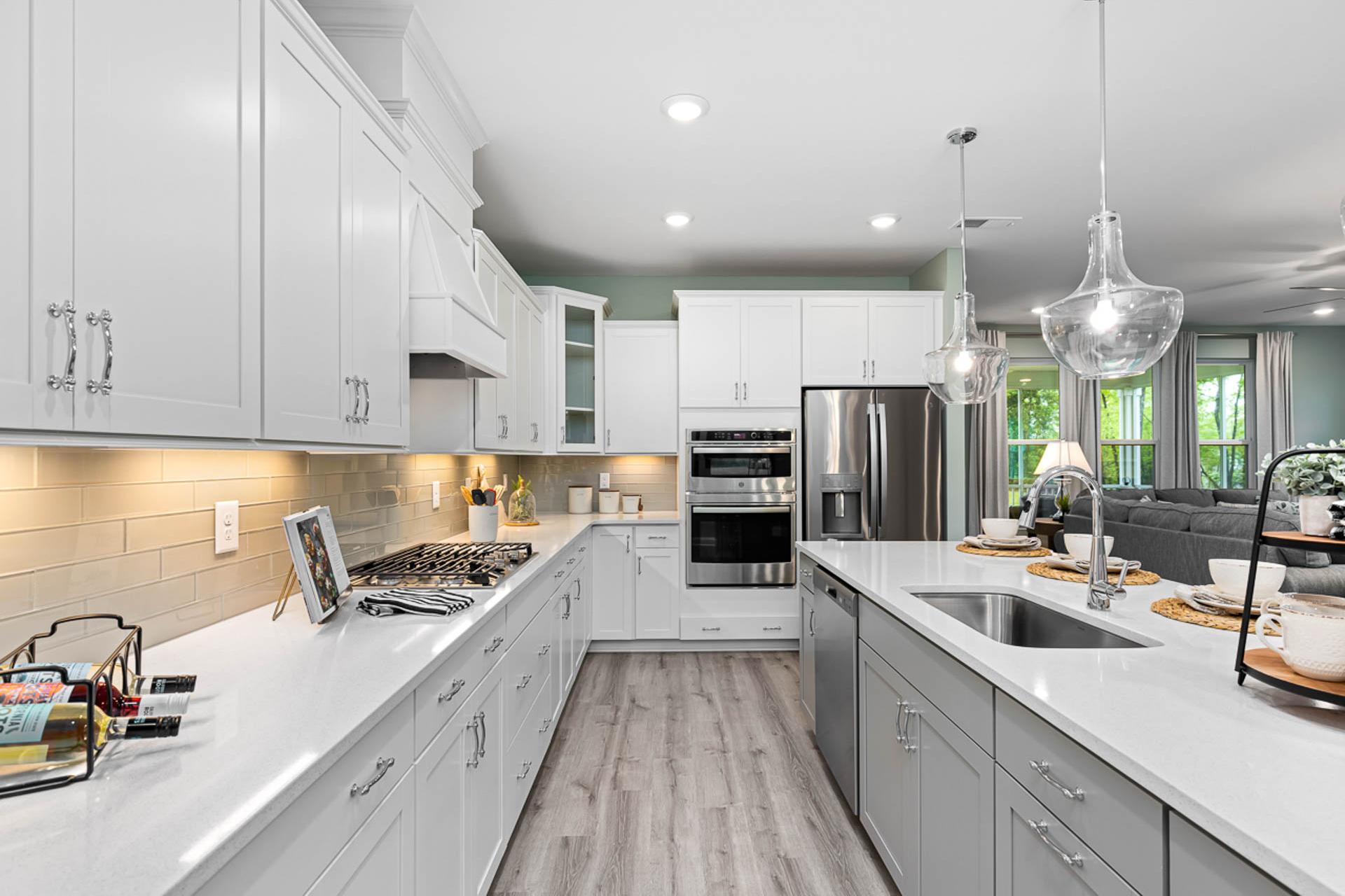 Spacious modern kitchen at Weatherford East in Angier NC with white shaker cabinets, gray island, stainless appliances, hardwood floors
