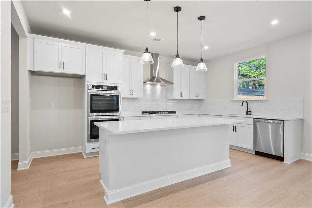 Modern white kitchen with quartz island, stainless steel appliances, double oven in Davidson Homes Hickory B, Buford, GA