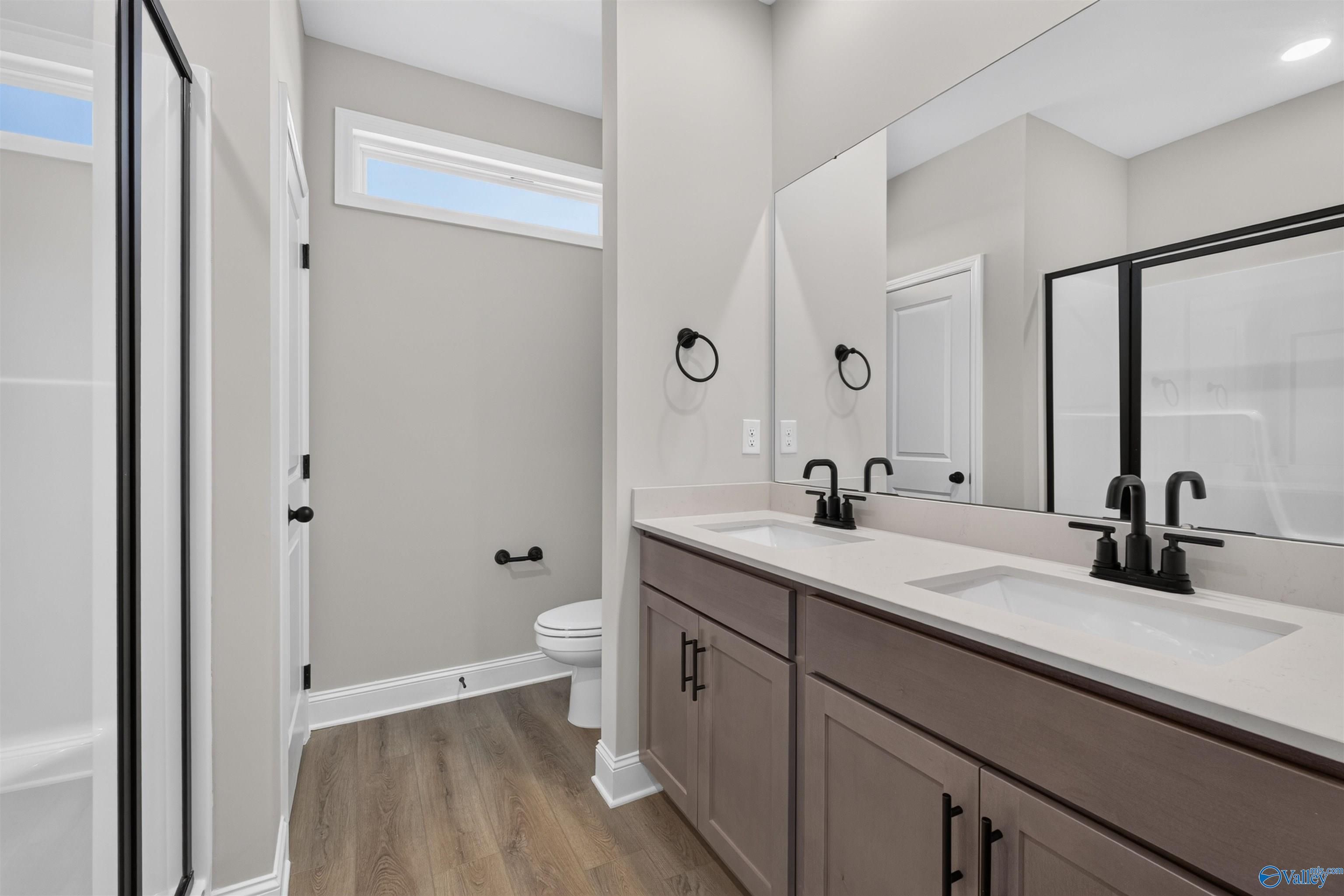 Modern primary bathroom with double vanity, matte black fixtures, and walk-in shower in Davidson Homes The Butler, New Market AL