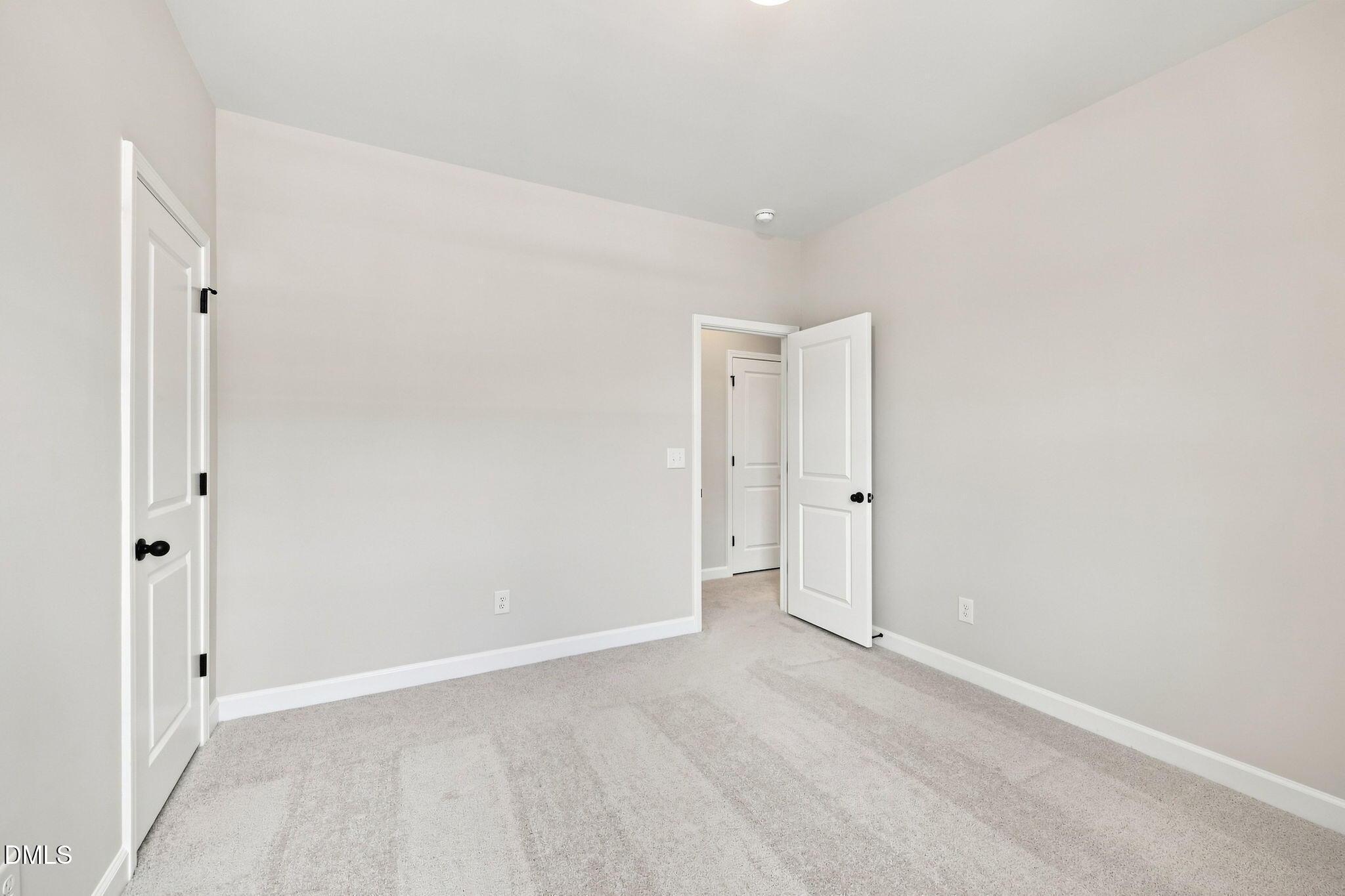 Neutral bedroom with plush carpet and white doors in The Harris C floor plan at Forestville Yard in Knightdale, NC.