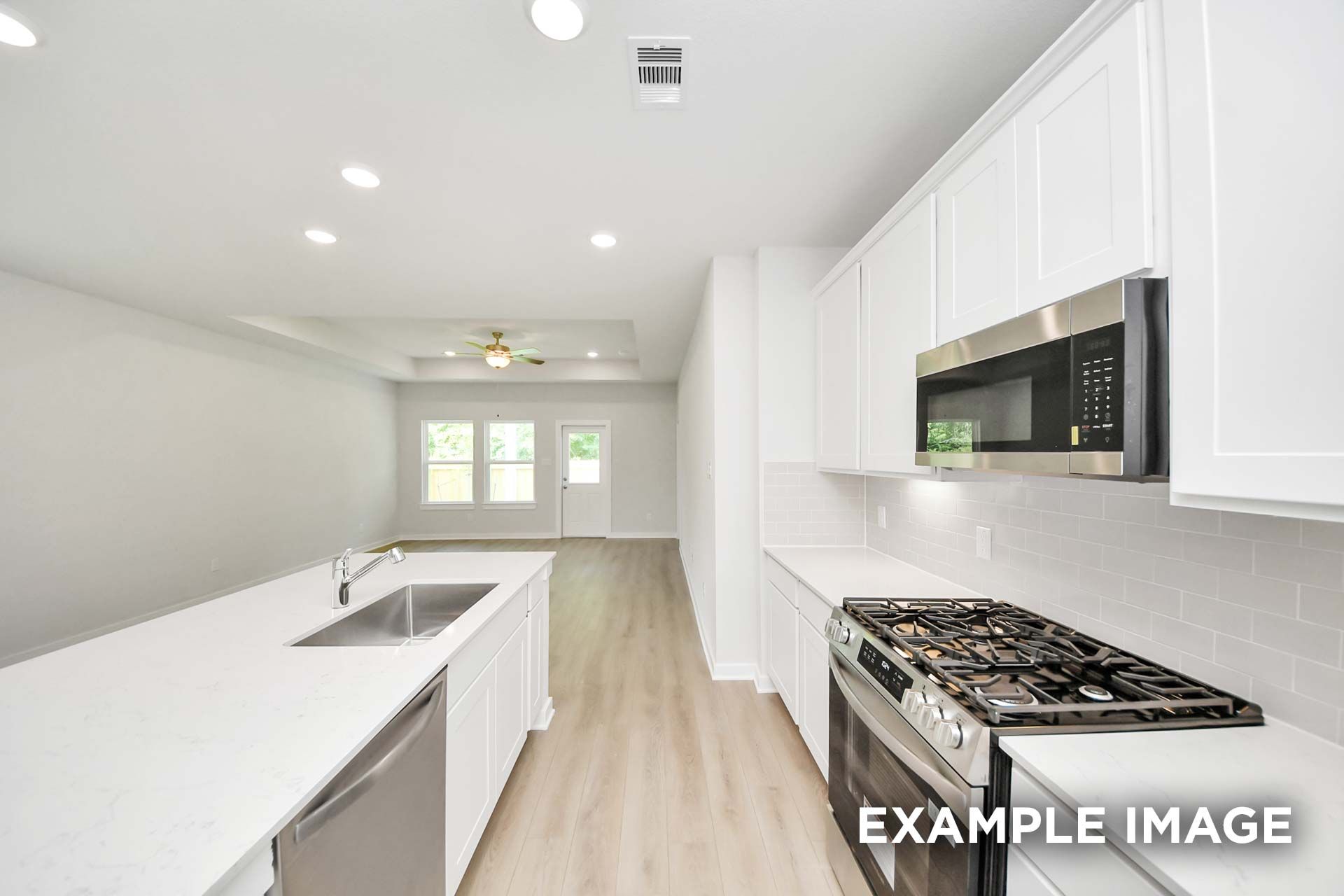 Bright kitchen with white cabinetry, quartz island, and stainless gas range in The Blanco by Davidson Homes, Beasley, TX