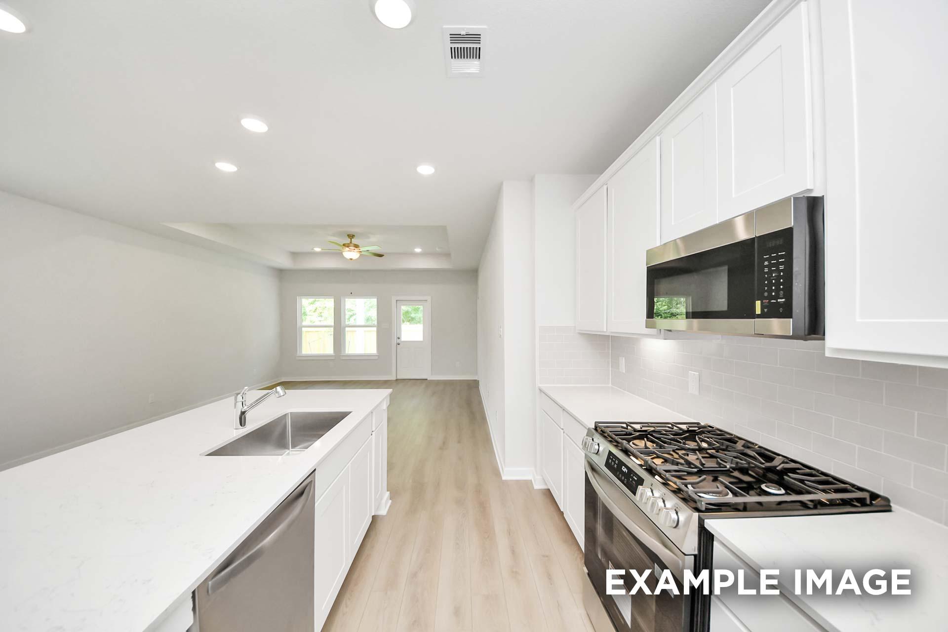 Bright kitchen with white cabinetry, quartz island, and stainless gas range in The Blanco by Davidson Homes, Beasley, TX