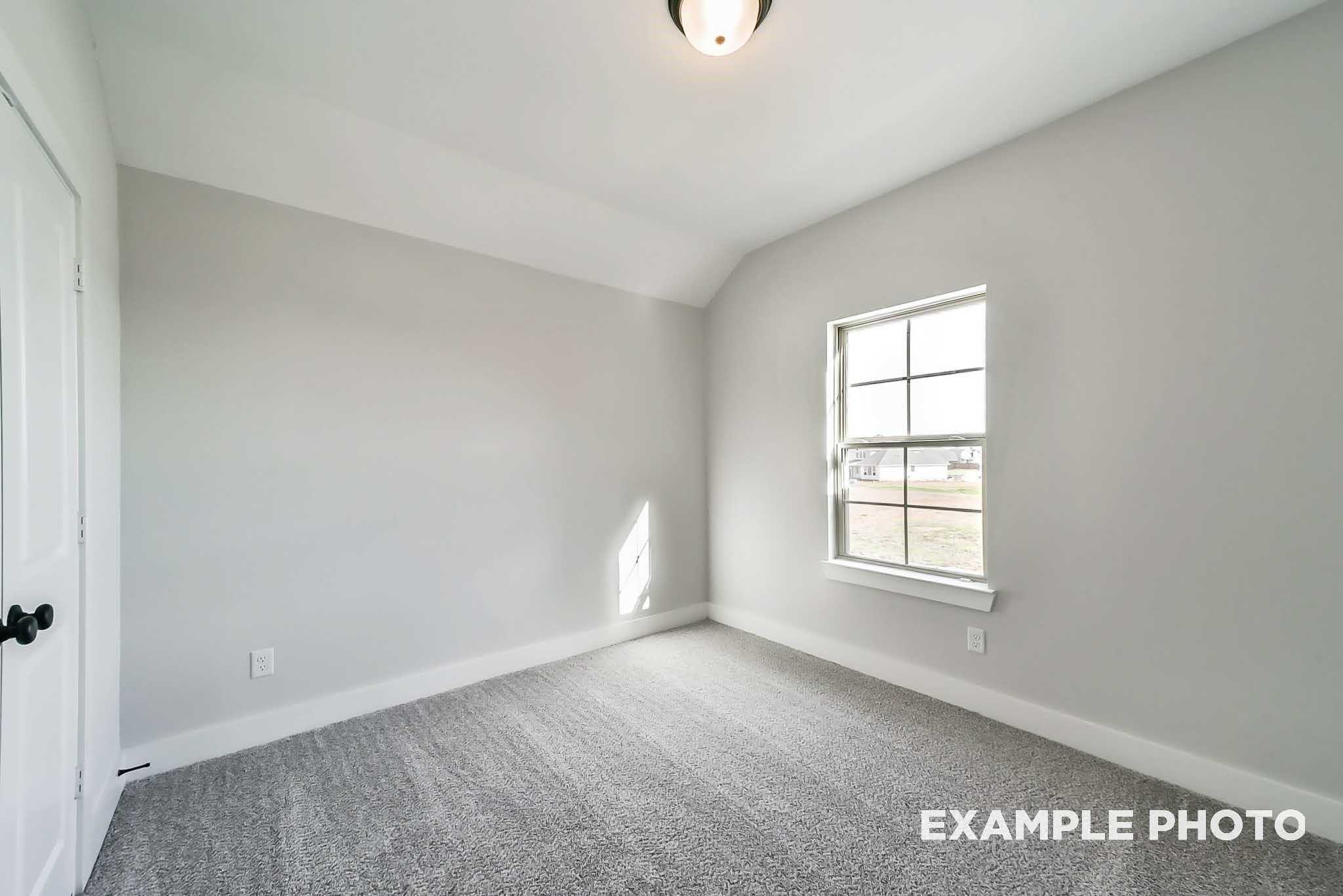 Bright secondary bedroom with gray walls, carpet flooring, and large window in Davidson Homes The Philip C, Rosharon, Texas