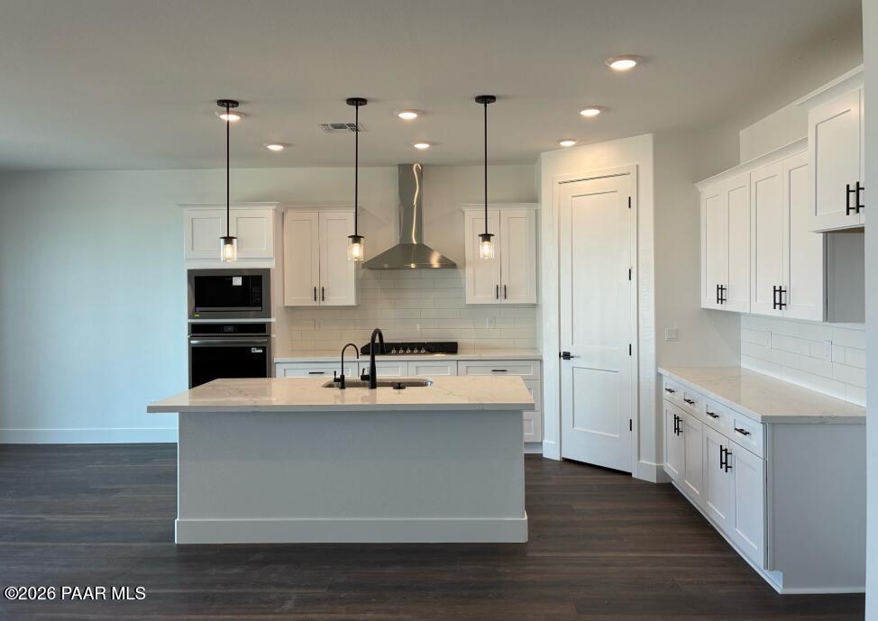 Modern kitchen with white cabinets, quartz island, and stainless appliances in The Durango II G at South Ranch, Prescott.