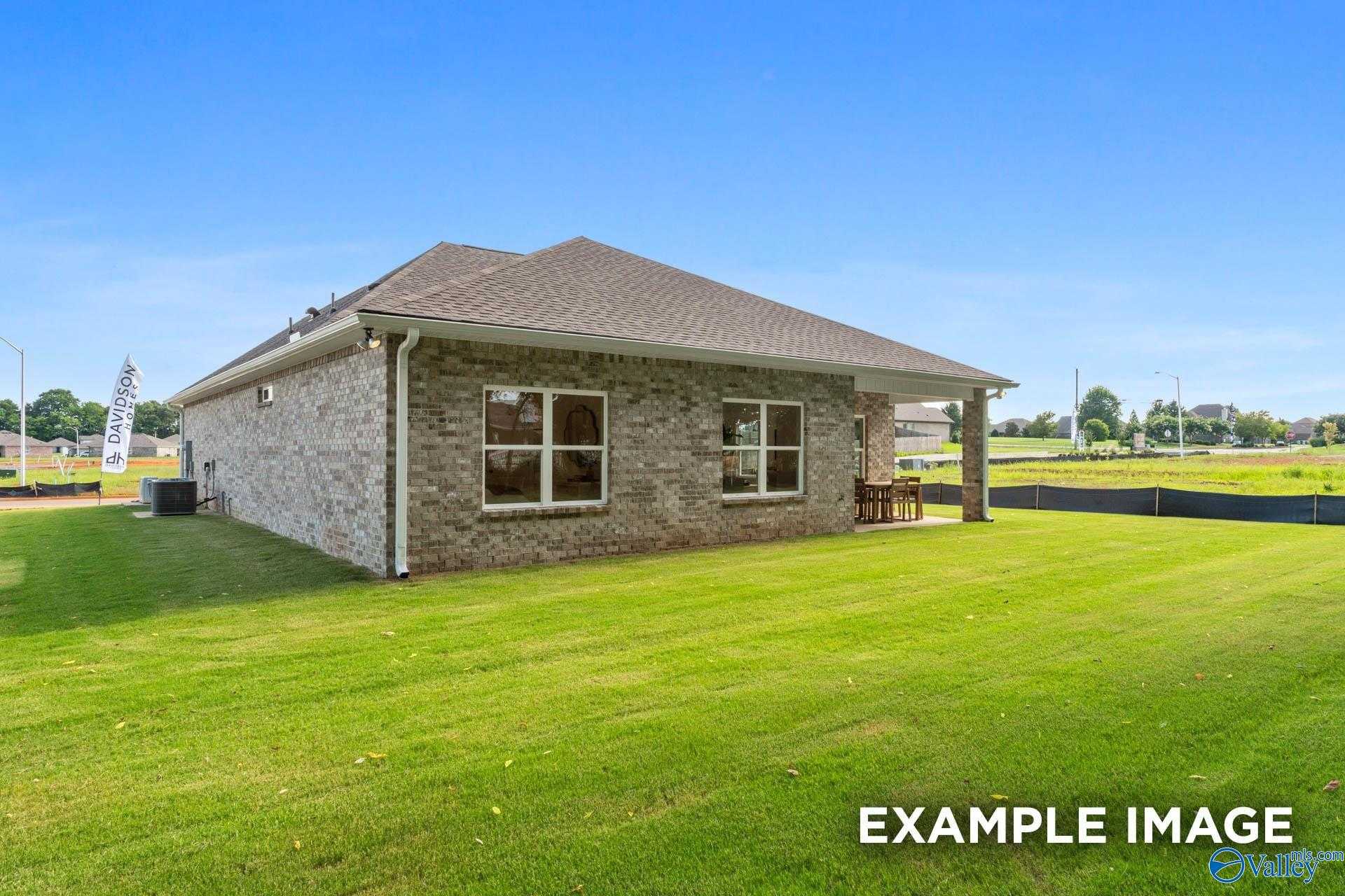 Brick single-story 3-bedroom home with covered patio, outdoor seating, and lush green lawn in Jaguar Hills, Huntsville, Alabama