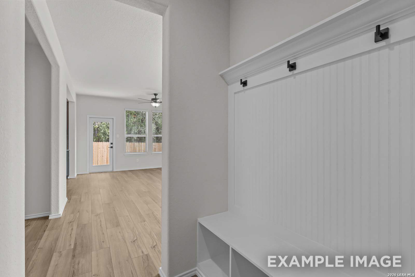 White mudroom bench with coat hooks in a Davidson Homes The Florence D floor plan in Cedar Heights, San Antonio, Texas.