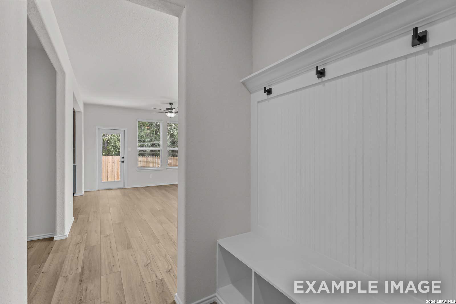 White mudroom bench with coat hooks in a Davidson Homes The Florence D floor plan in Cedar Heights, San Antonio, Texas.