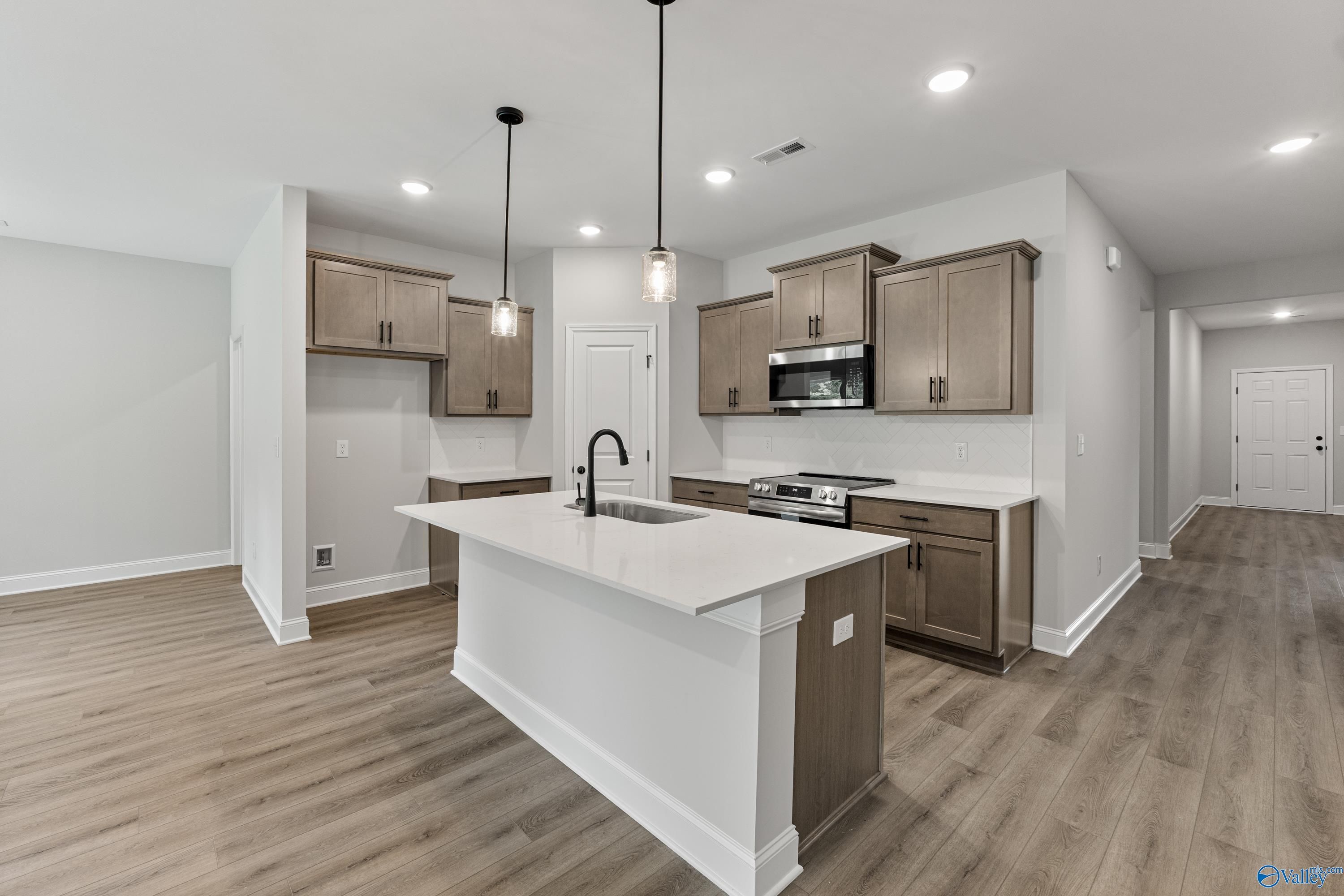 Modern kitchen with warm wood cabinets, white quartz island sink, stainless range in Davidson Homes The Daphne, Huntsville AL