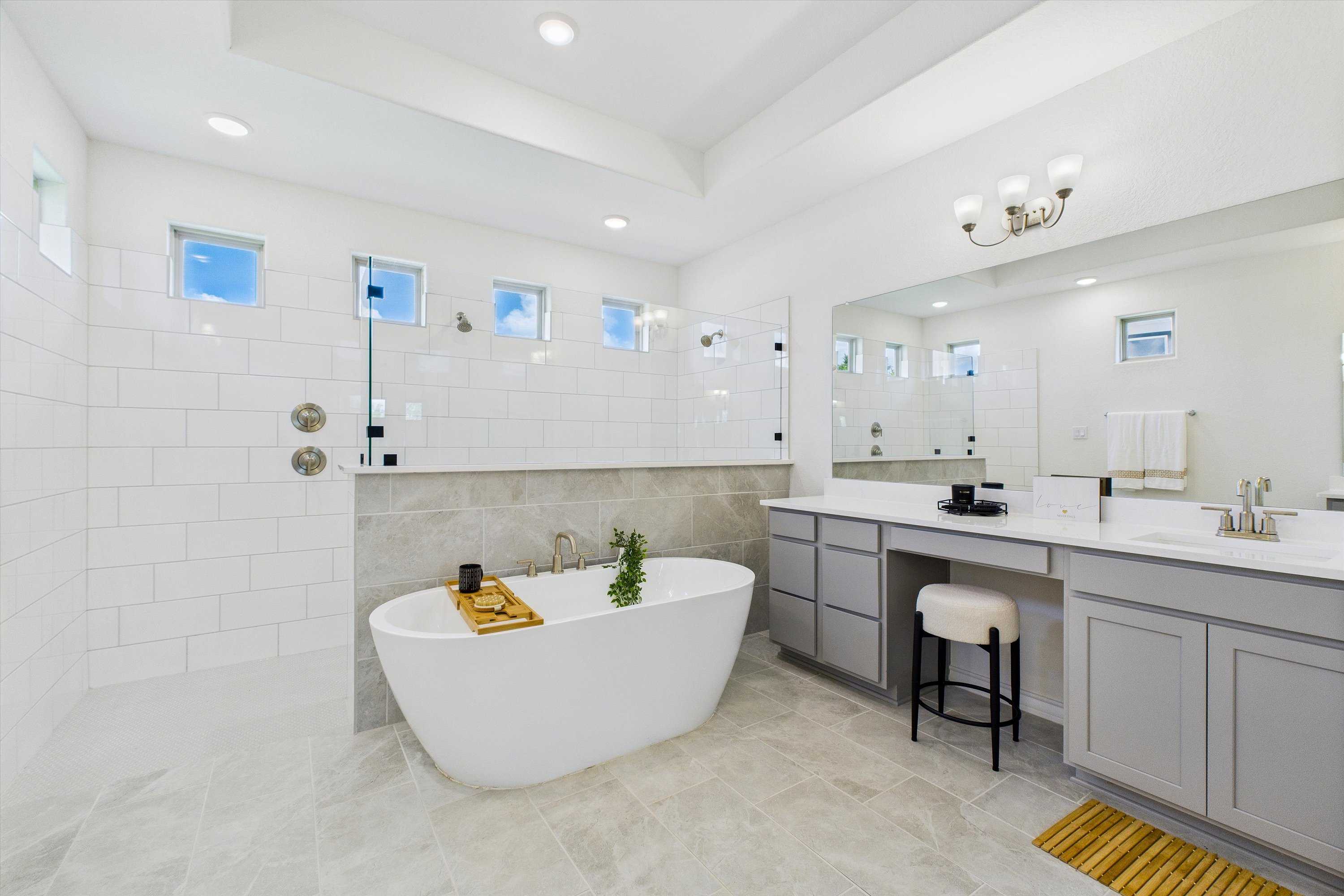 Elegant master bathroom with freestanding tub, double gray vanity, subway tile shower in Davidson Homes The Summerlin C, Castroville, Texas